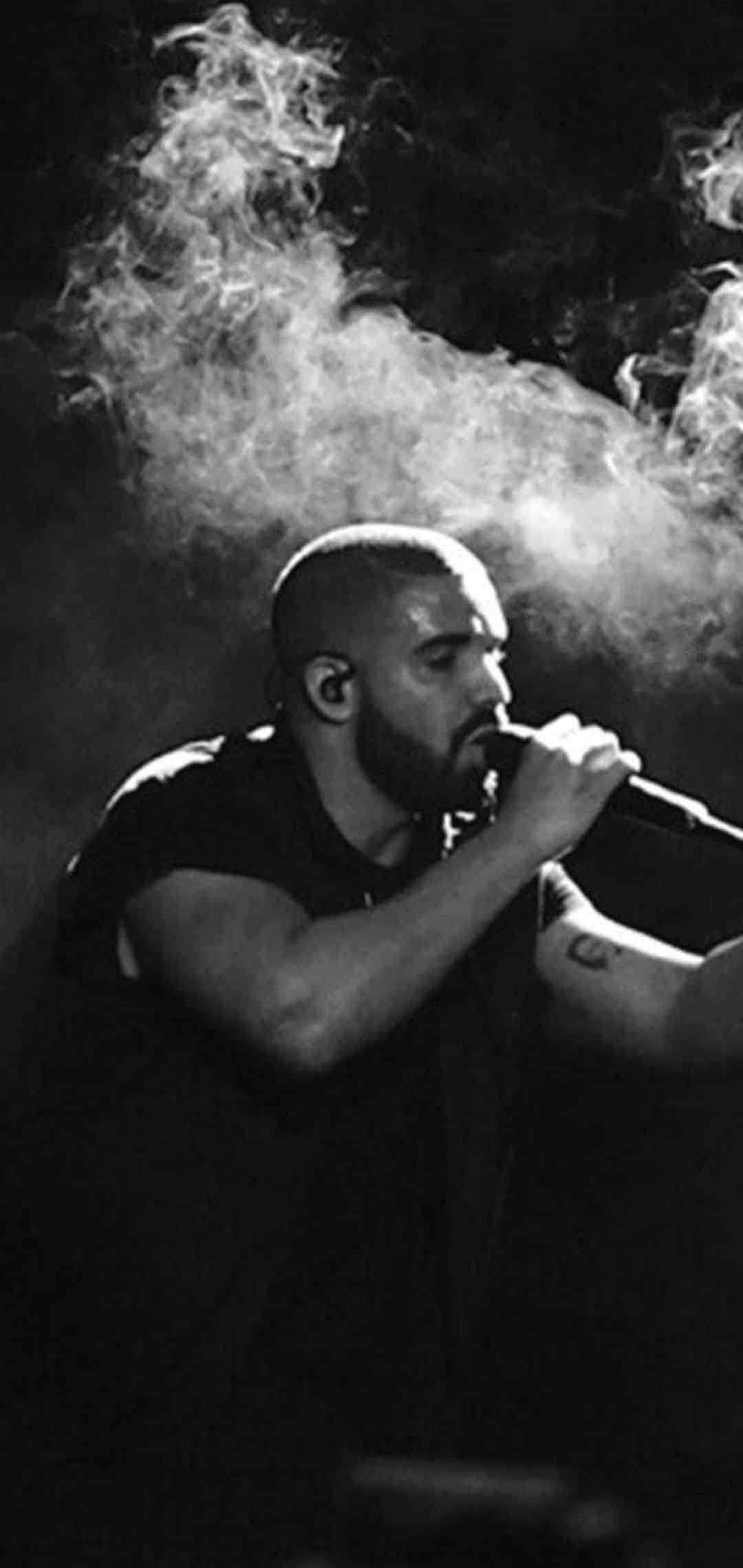 Drake 桌布 壁紙 — 一個光頭鬍鬚男對著咪高峰唱歌，身後煙霧翻騰的黑白照片。