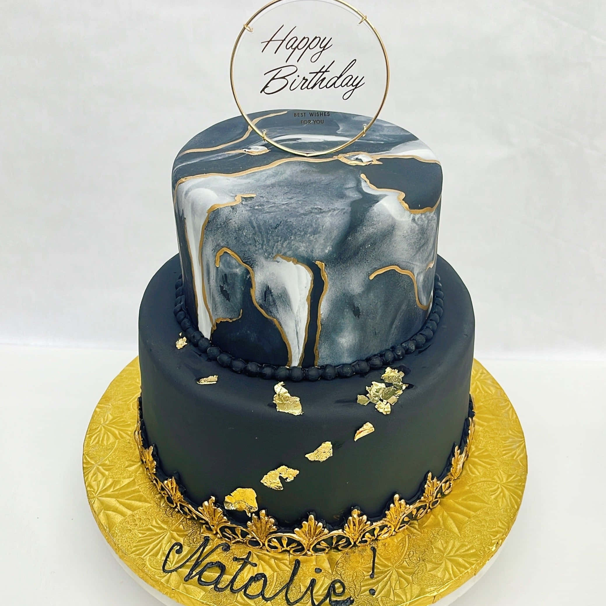 Cake Fondant 桌布 壁紙 — 一個兩層生日蛋糕，採用黑色大理石翻糖和金箔裝飾，放在金色圖案托盤上，並有 'Happy Birthday' 裝飾牌。
