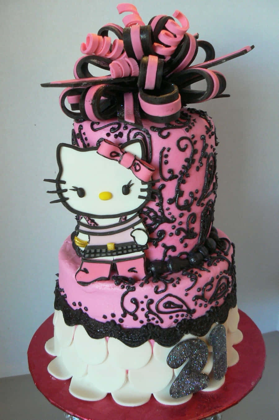 Hello Kitty Birthday 桌布 壁紙 — 一個兩層粉紅色蛋糕，帶有黑色漩渦，頂部有一個Hello Kitty公仔和一個大粉紅色和黑色蝴蝶結。