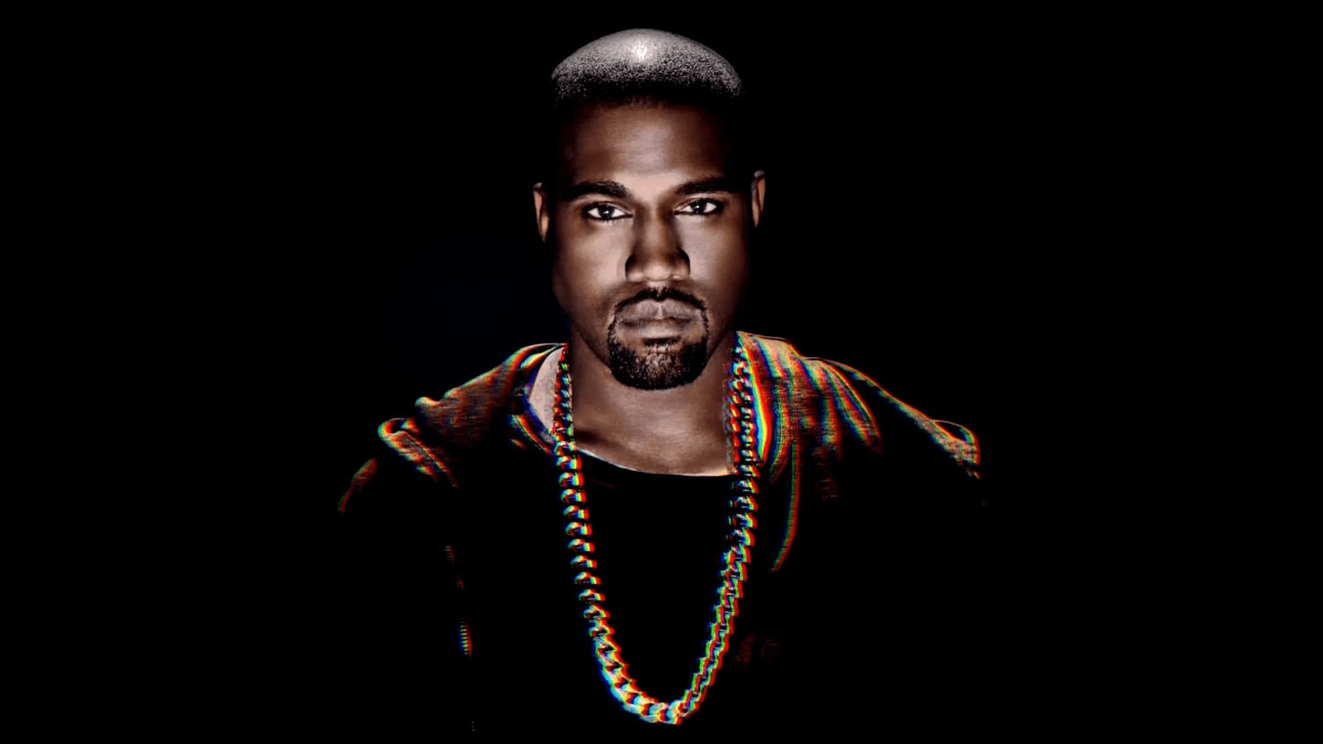 Kanye 桌布 壁紙 — 一個剃光頭和鬍鬚的男人，穿著彩色鏈條和圖案襯衫，在黑色背景下強烈凝視。