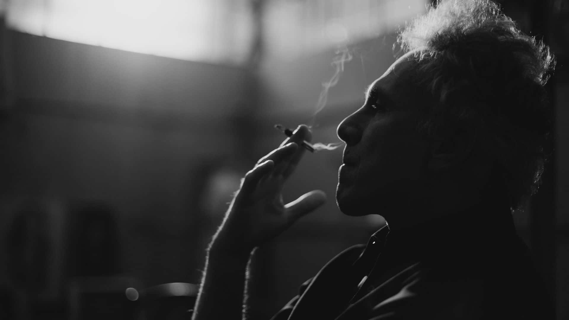 吸煙 桌布 壁紙 — 一個剪影中的男人正在吸煙，煙霧在明亮的窗戶背景下向上繚繞。