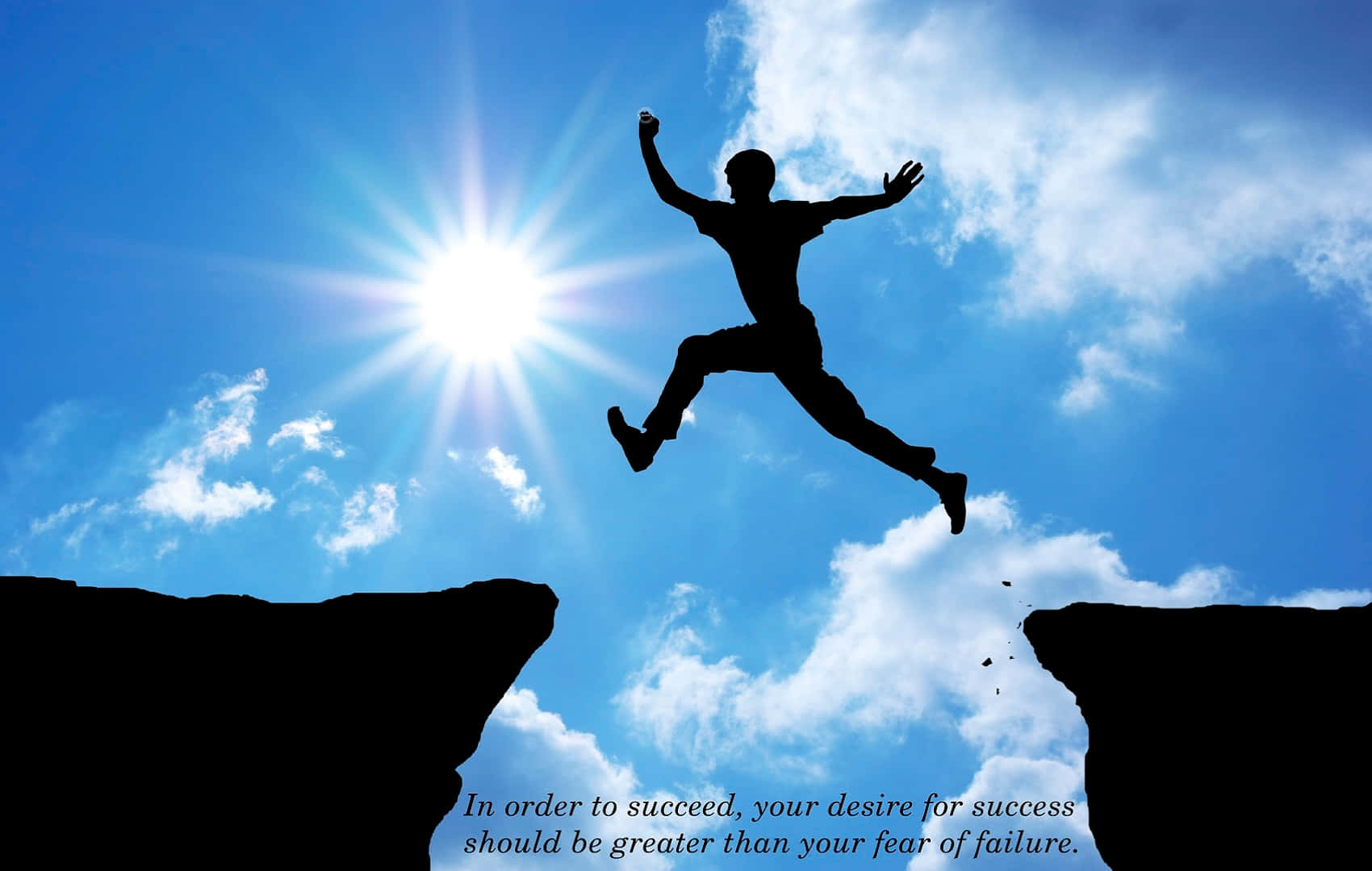 Success 桌布 壁紙 — 一個剪影人物在明亮的太陽、耀眼的光芒和散落的雲朵下，動態地跳躍於兩個懸崖之間。