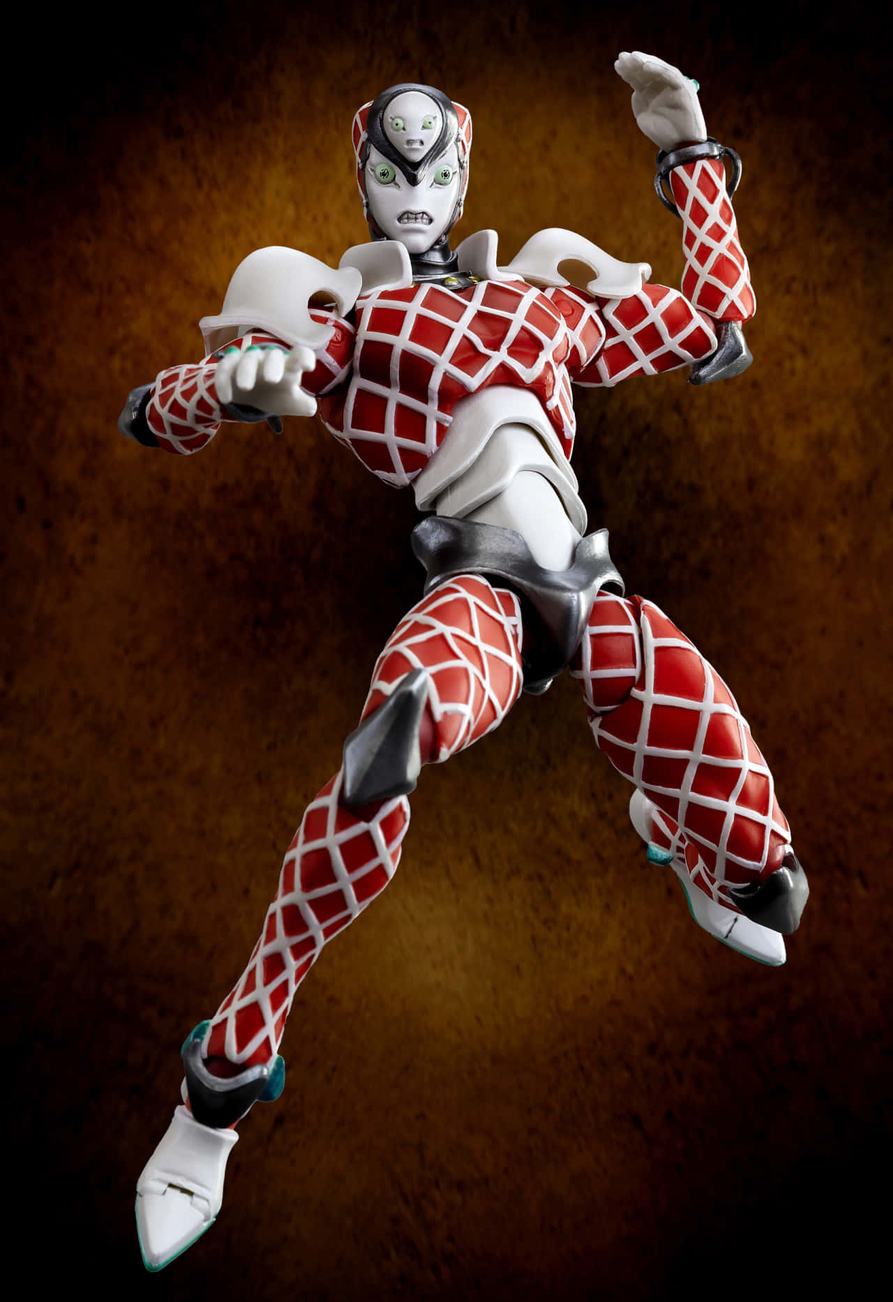 Jojo King Crimson 桌布 壁紙 — 一個動感十足的動漫風格可動人偶，身穿紅白格紋盔甲，在帶有紋理的棕色背景前做出跳躍姿勢。