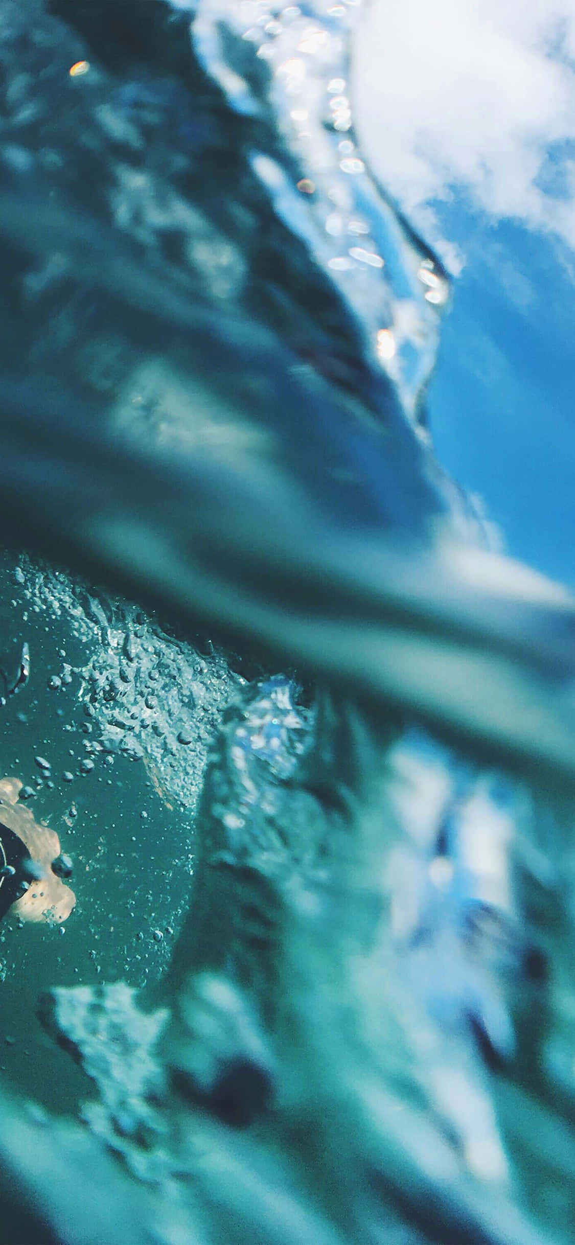 夏天 iPhone 桌布 壁紙 — 一個動態的水底視角，透過漣漪的藍色水面仰望帶有雲朵的明亮天空。