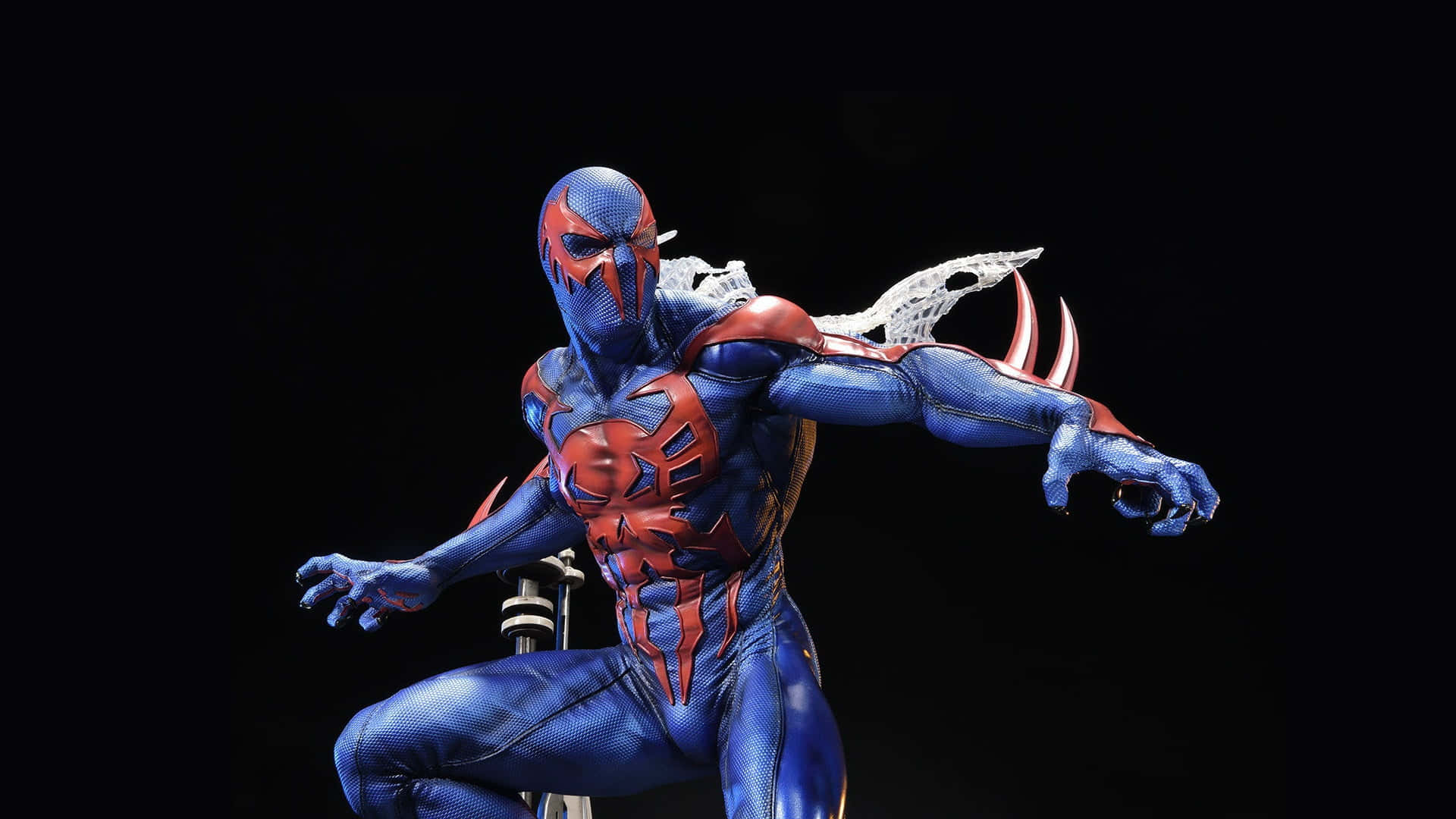 Spider Man 2099 桌布 壁紙 — 一個動態的藍色和紅色蜘蛛俠人偶，帶有白色蛛網翅膀，以英雄姿態蹲伏在黑色背景前。