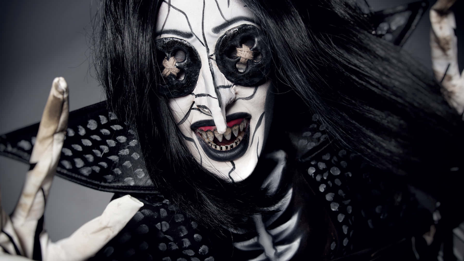 Halloween Makeup 桌布 壁紙 — 一個化著骷髏妝、黑髮的人，在黑暗背景下擺出威脅姿勢。