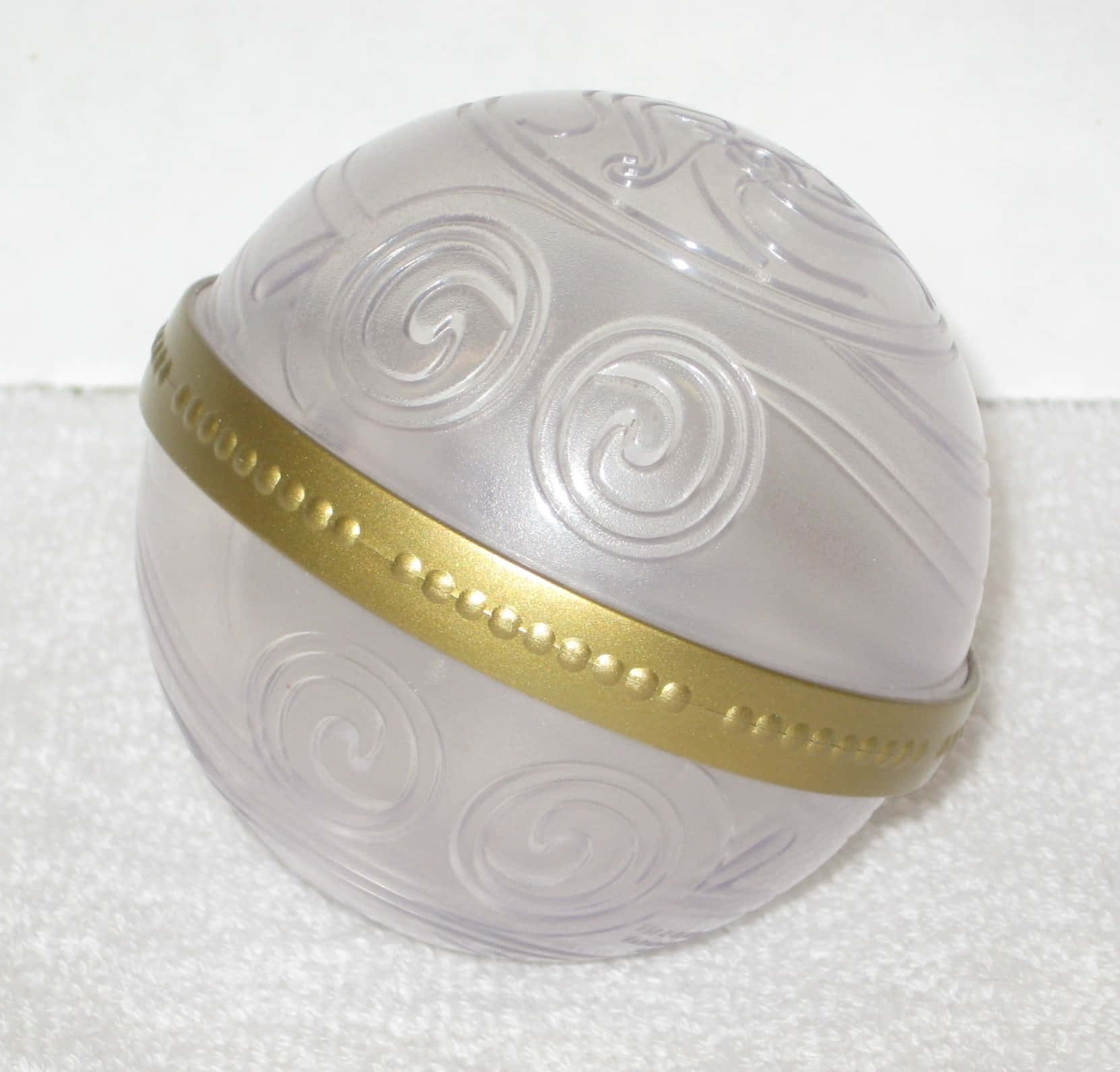 Mystical Artifacts 桌布 壁紙 — 一個半透明磨砂玻璃球，帶有浮雕漩渦圖案和金色珠飾帶，放置在白色紋理表面上。