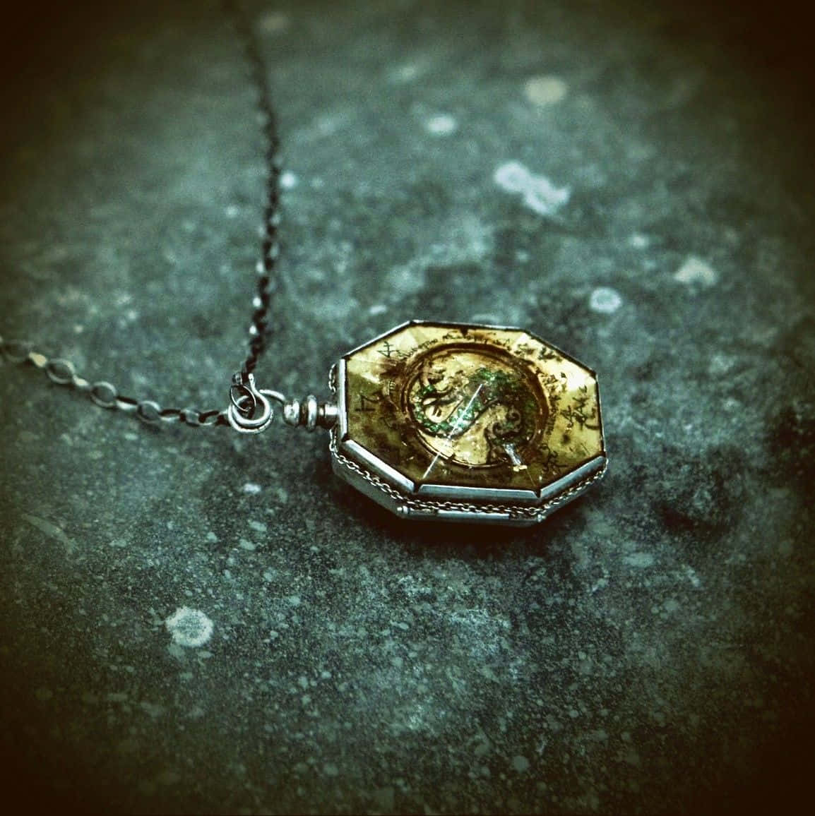 Horcrux 桌布 壁紙 — 一個古董八角形懷錶，帶有暗淡的金色錶盤，放置在風化的灰色石頭表面上。