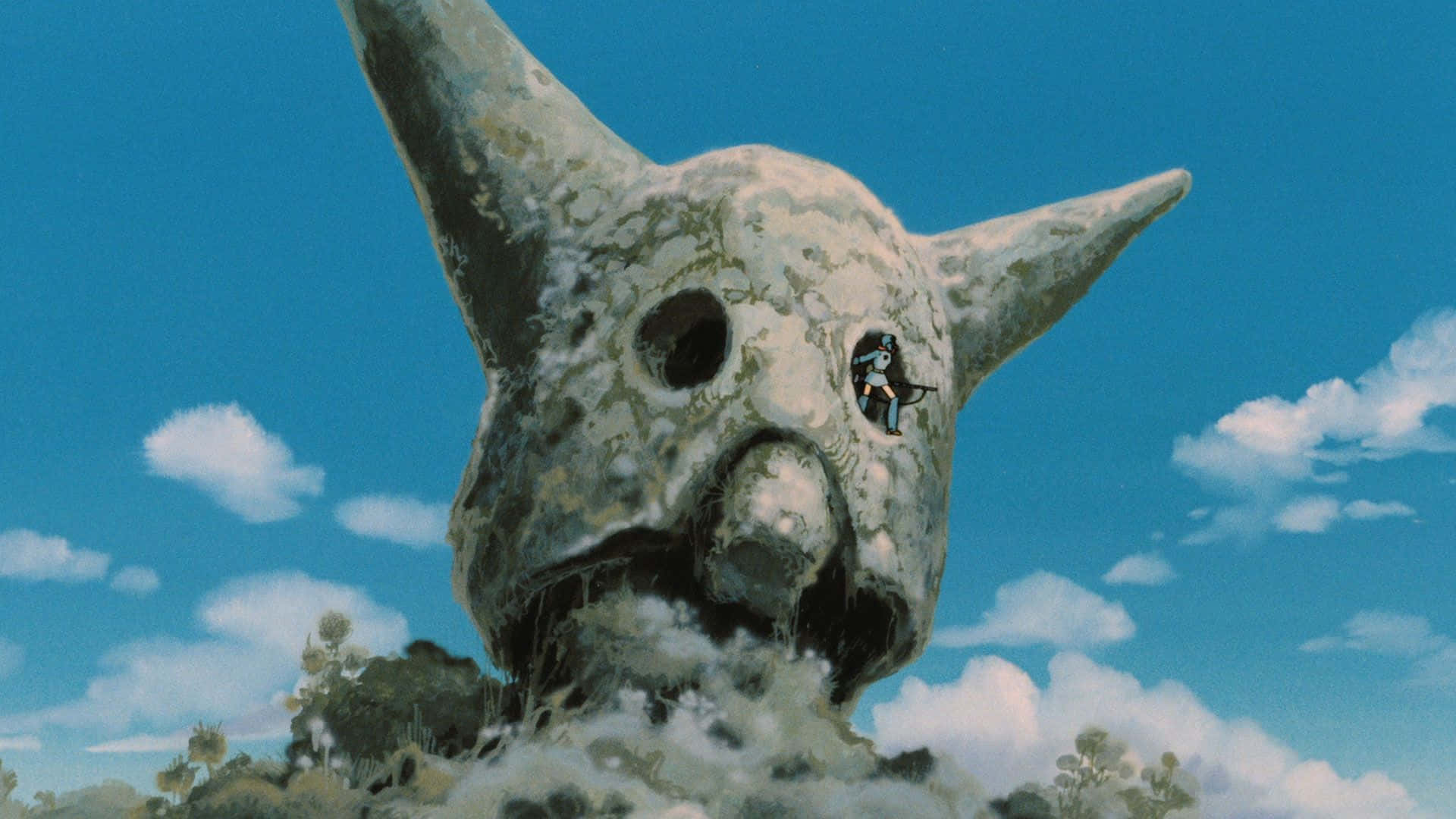 nausicaä of the valley of the wind 桌布 壁紙 — 一個只有一個眼窩的巨型石頭怪物，在洞穴般的嘴裡叼著一個小戰士，背景是明亮的藍天。
