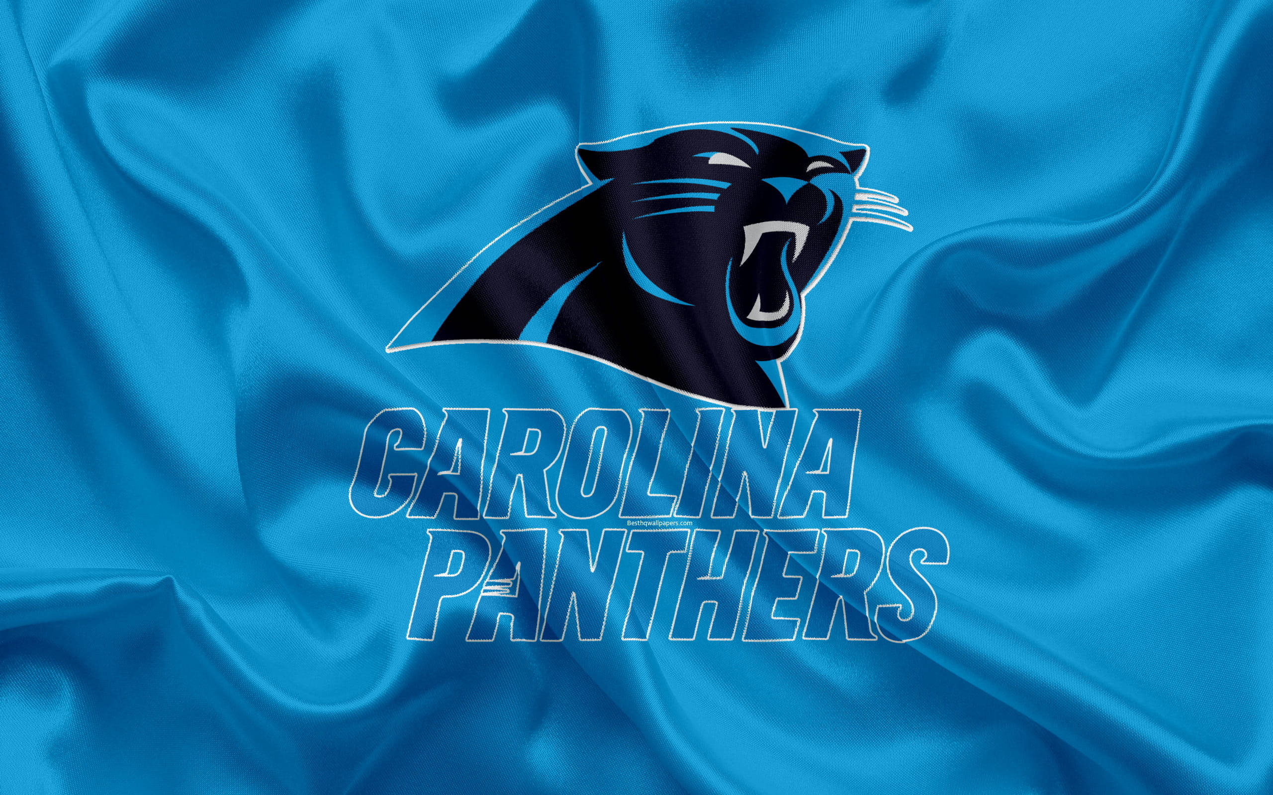  壁紙 — 一個咆哮的黑豹標誌，上面有「CAROLINA PANTHERS」文字，背景是流動的皇家藍色緞面布料。