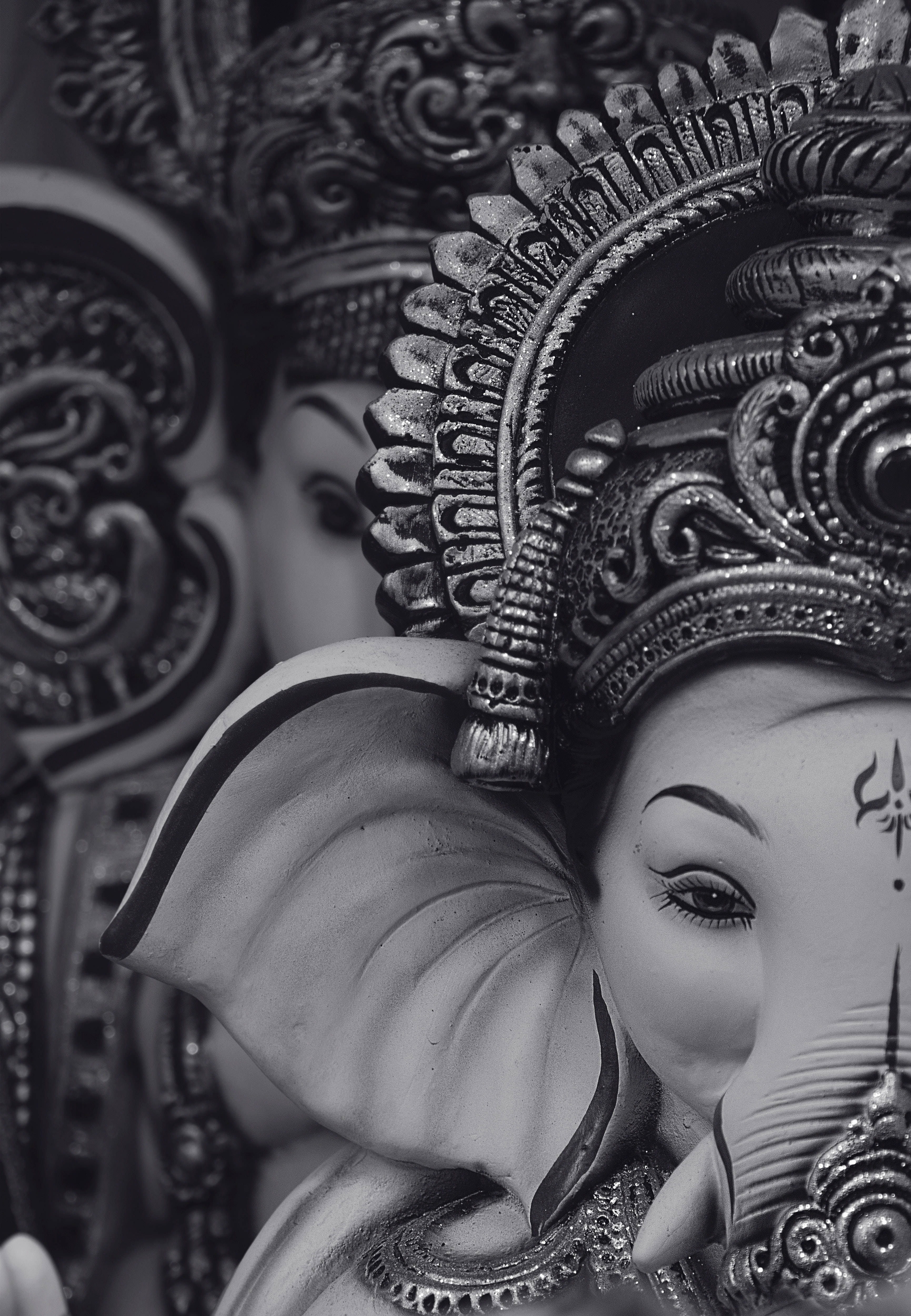 ganesh black and white 桌布 壁紙 — 一個單色特寫，展示一尊細節精緻、帶有華麗頭飾和大象特徵的象頭神雕像。