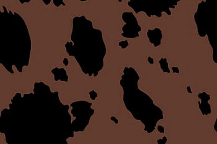 Brown Cow Print 桌布 壁紙 — 一個大膽的圖案，不規則的黑色形狀散落在豐富的棕色背景上。