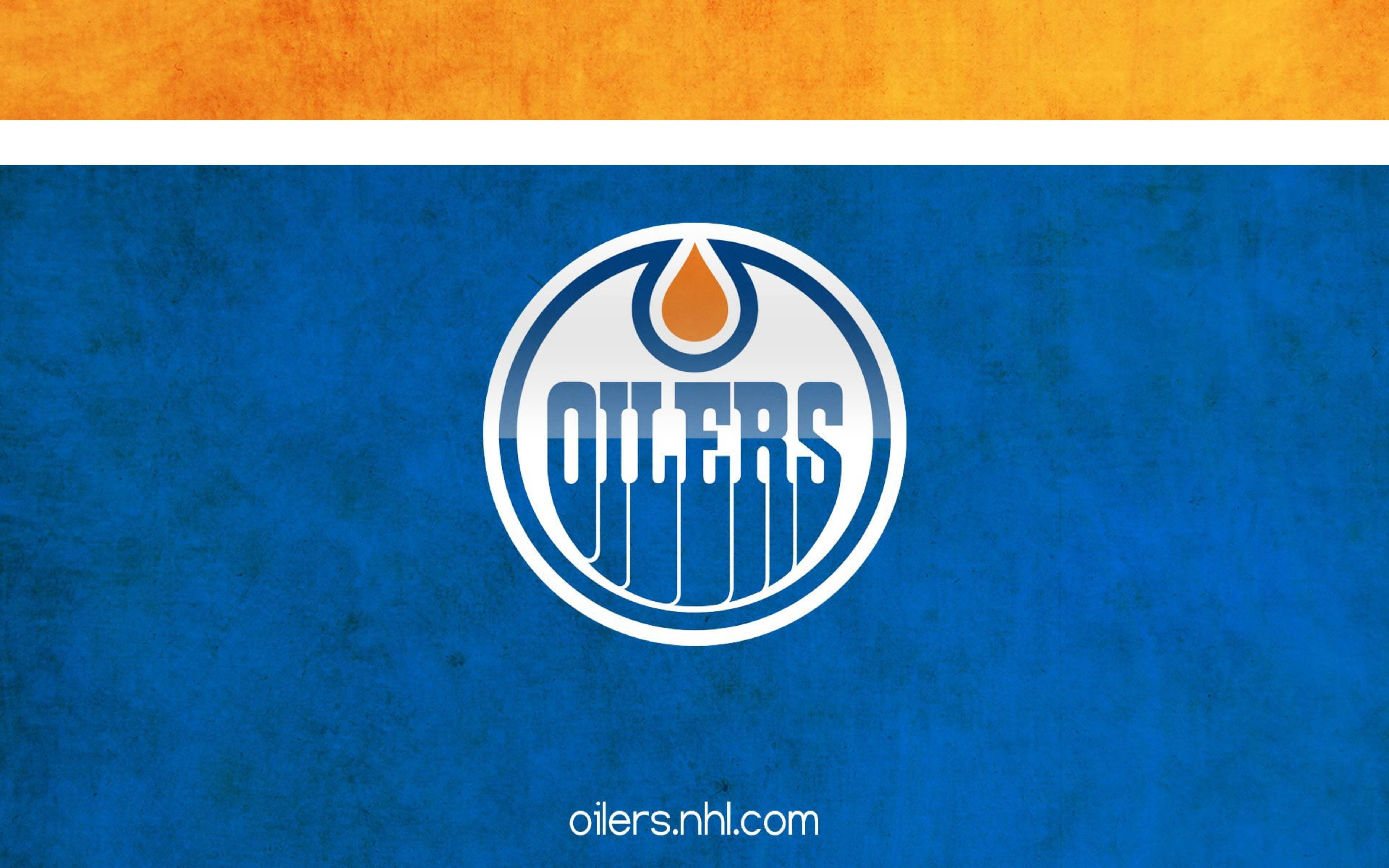 Edmonton Oilers 桌布 壁紙 — 一個大膽的愛民頓油人隊標誌，居中於帶有紋理的藍色背景上，上方有一條橙色條紋。