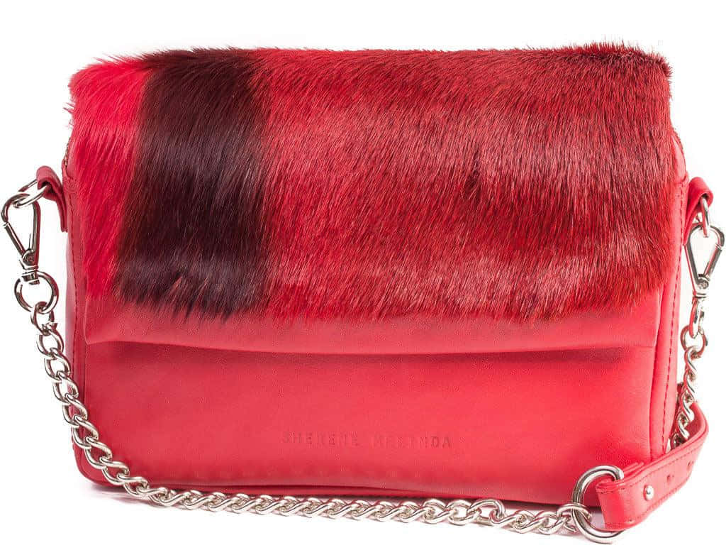 Red Handbag 桌布 壁紙 — 一個大膽的紅色手袋，配有仿皮草翻蓋和銀色鏈條肩帶，背景為白色。