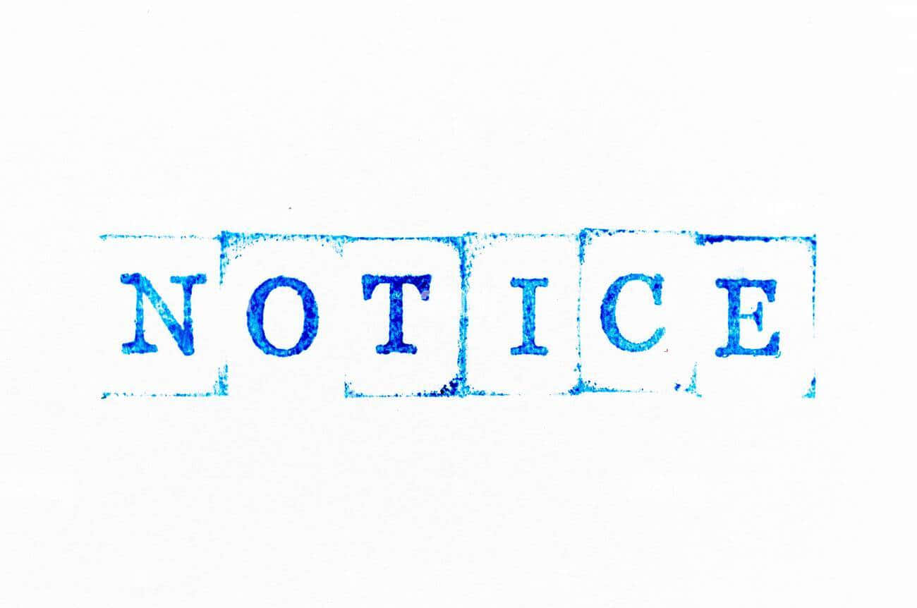 Notice 桌布 壁紙 — 一個大膽的藍色墨水印章印記，上面寫著「NOTICE」，印在帶有可見紋理和輕微污跡的純白紙上。
