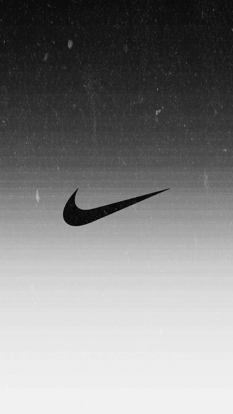 Nike 桌布 壁紙 — 一個大膽的黑色Nike勾勾標誌漂浮在帶有紋理的灰階漸變背景上。