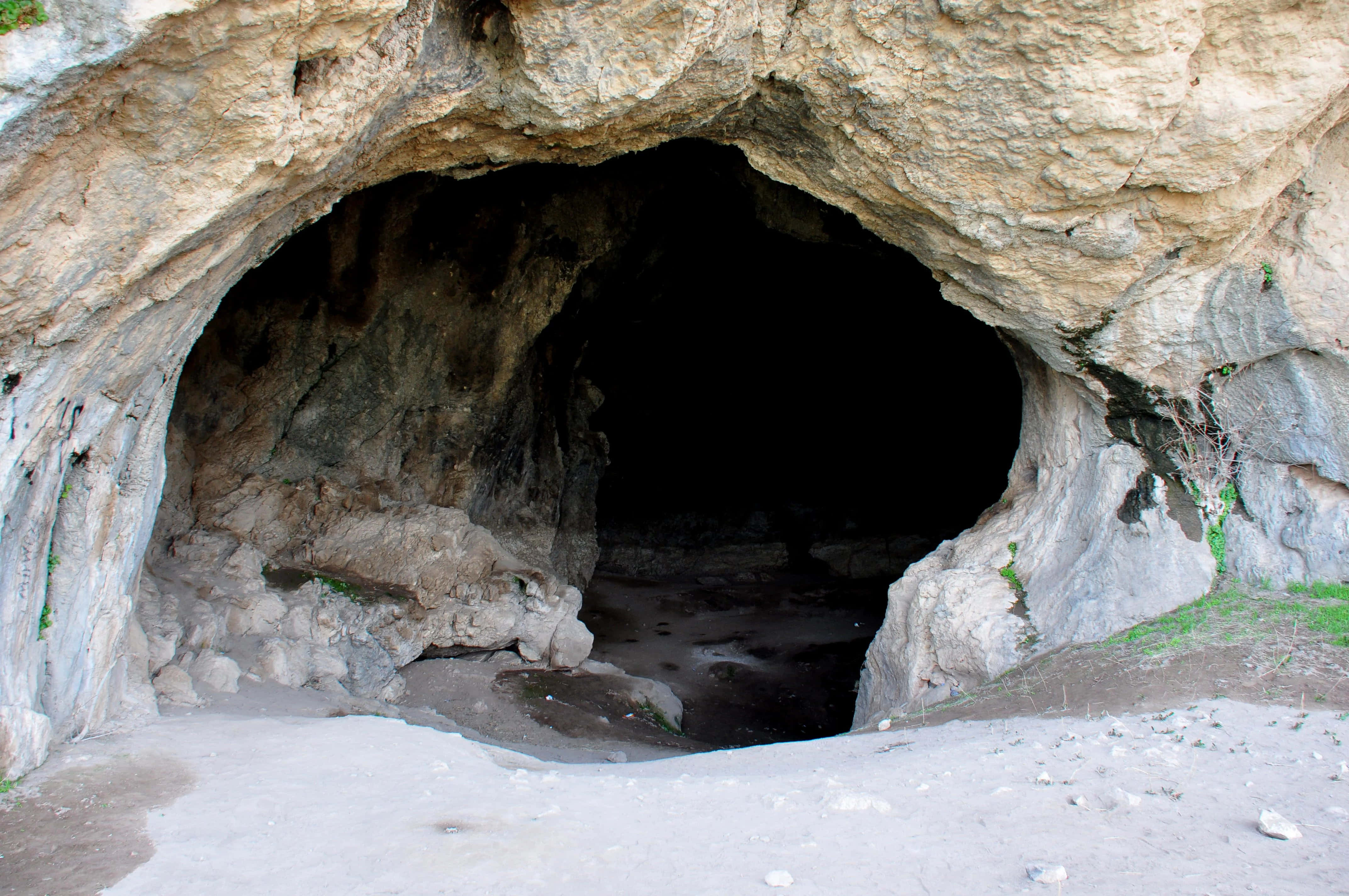 Cave 桌布 壁紙 — 一個天然岩石洞穴入口，擁有堅固的米色石牆和黑暗神秘的內部。