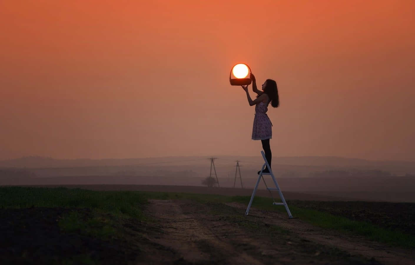 Sunset Photography 桌布 壁紙 — 一個女孩在日落時站在梯子上，手持一個模仿太陽的發光球體，背景是橙色的天空。