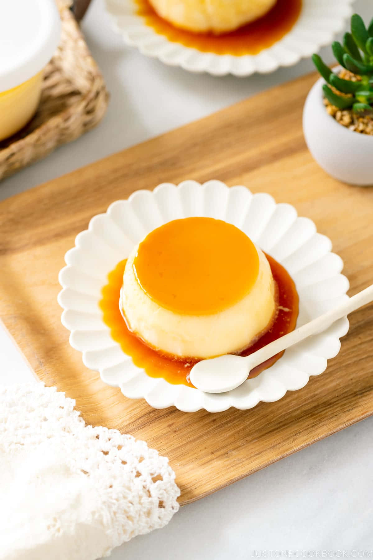 Japanese Sweets 桌布 壁紙 — 一個奶油焦糖布丁甜品在白色波浪紋碟上閃閃發光，放在木板上，旁邊有精緻的蕾絲餐巾。