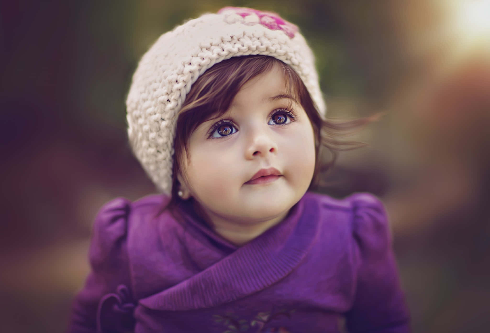 Baby Girl 桌布 壁紙 — 一個好奇嘅幼兒嘅近鏡，戴住忌廉色針織帽同紫色毛衣，瞪大眼向上望。