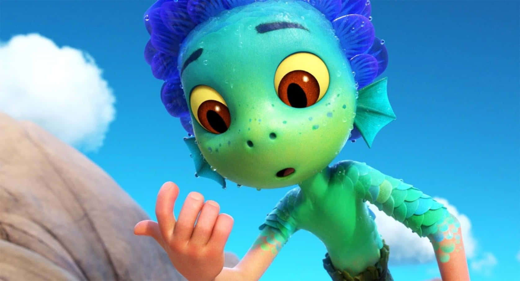 Luca 桌布 壁紙 — 一個好奇的動畫人魚小孩，擁有藍色尖刺頭髮和綠色鱗片，在藍天白雲下伸出手。