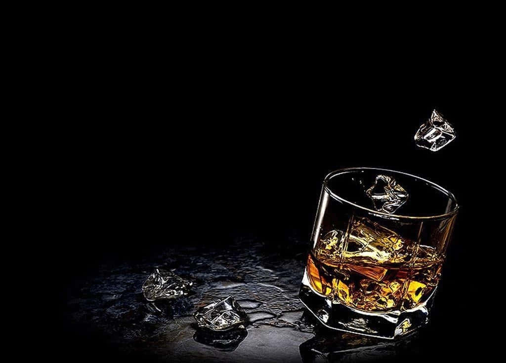 alcohol 桌布 壁紙 — 一個威士忌杯，杯中有冰塊，放在黑色背景下的深色潮濕表面上。