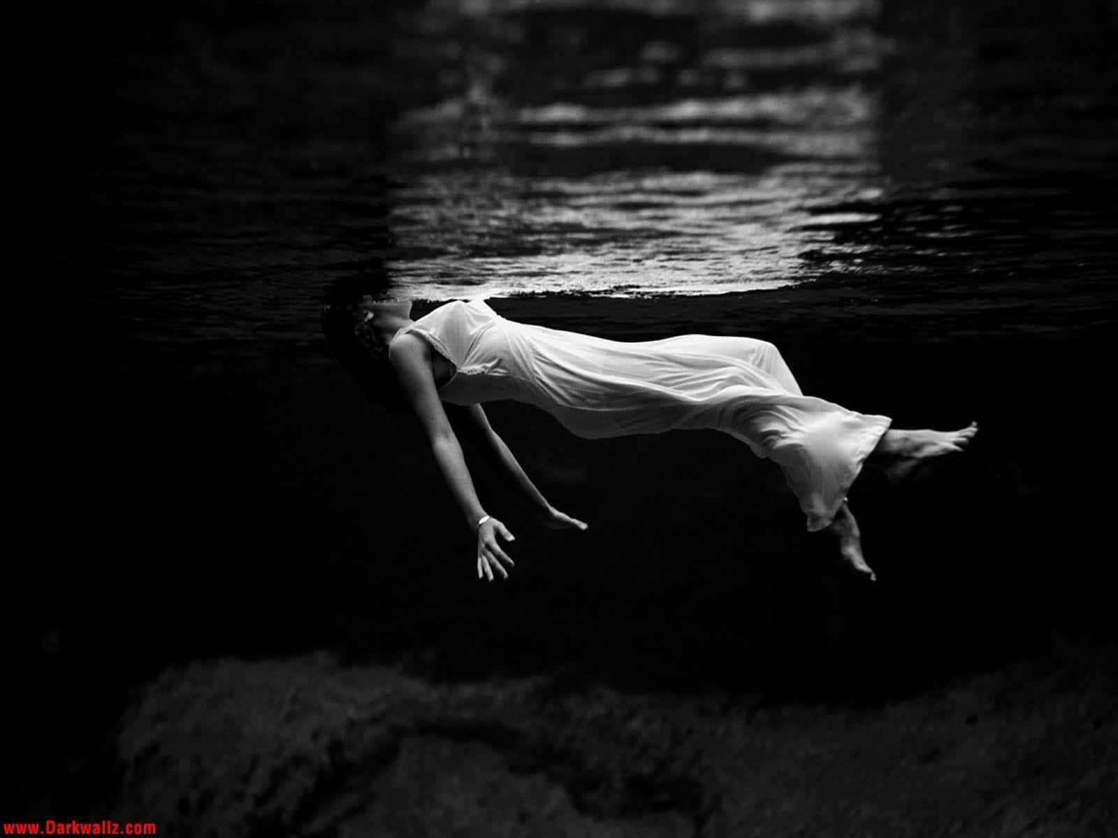 一個孤獨、沮喪的少女，正與抑鬱抗爭 壁紙 — 一位身穿飄逸白色連衣裙的女性，頭部露出水面，在水中寧靜地漂浮，呈現出鮮明的黑白構圖。