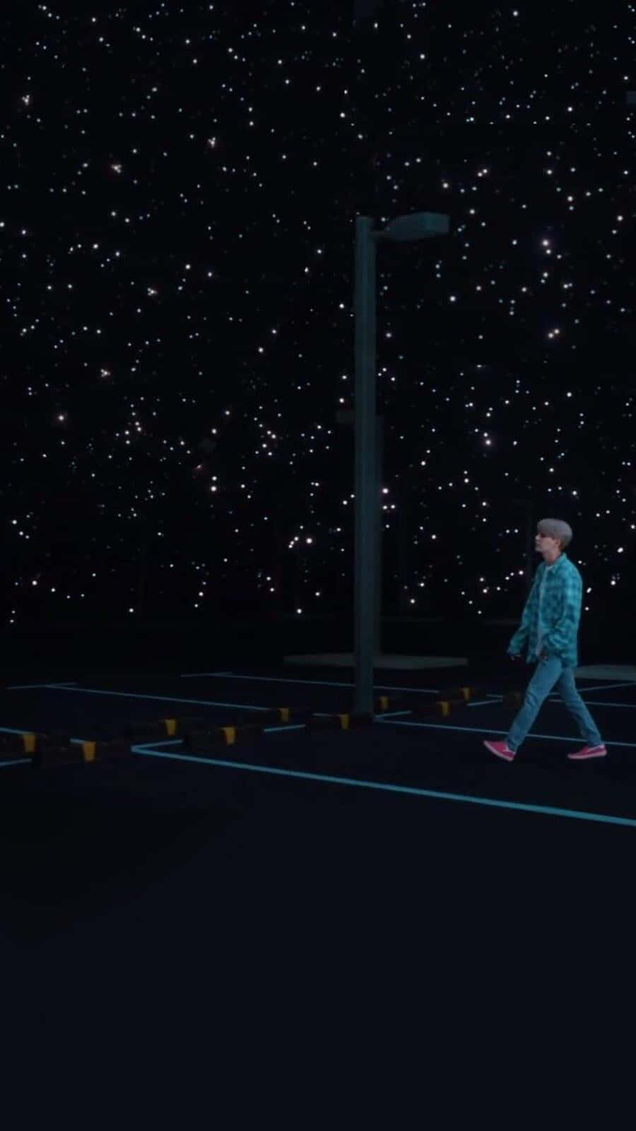Bts Mv 桌布 壁紙 — 一個孤獨的人喺佈滿星星嘅夜空下，行過一個空蕩蕩嘅停車場，附近有支高燈柱。