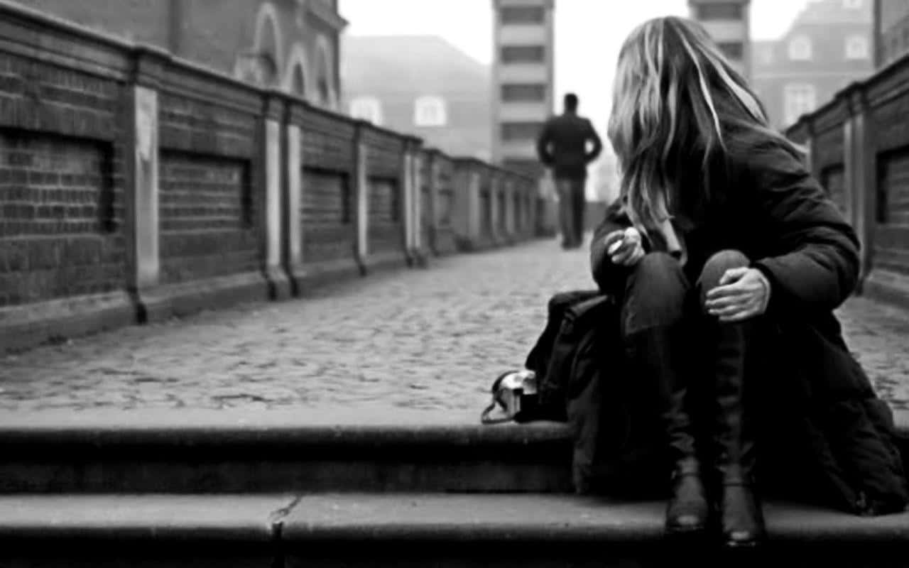 Sad Love 桌布 壁紙 — 一個孤獨的人蜷縮在單色城市小巷的石階上，另一個人影走進迷霧般的遠方。