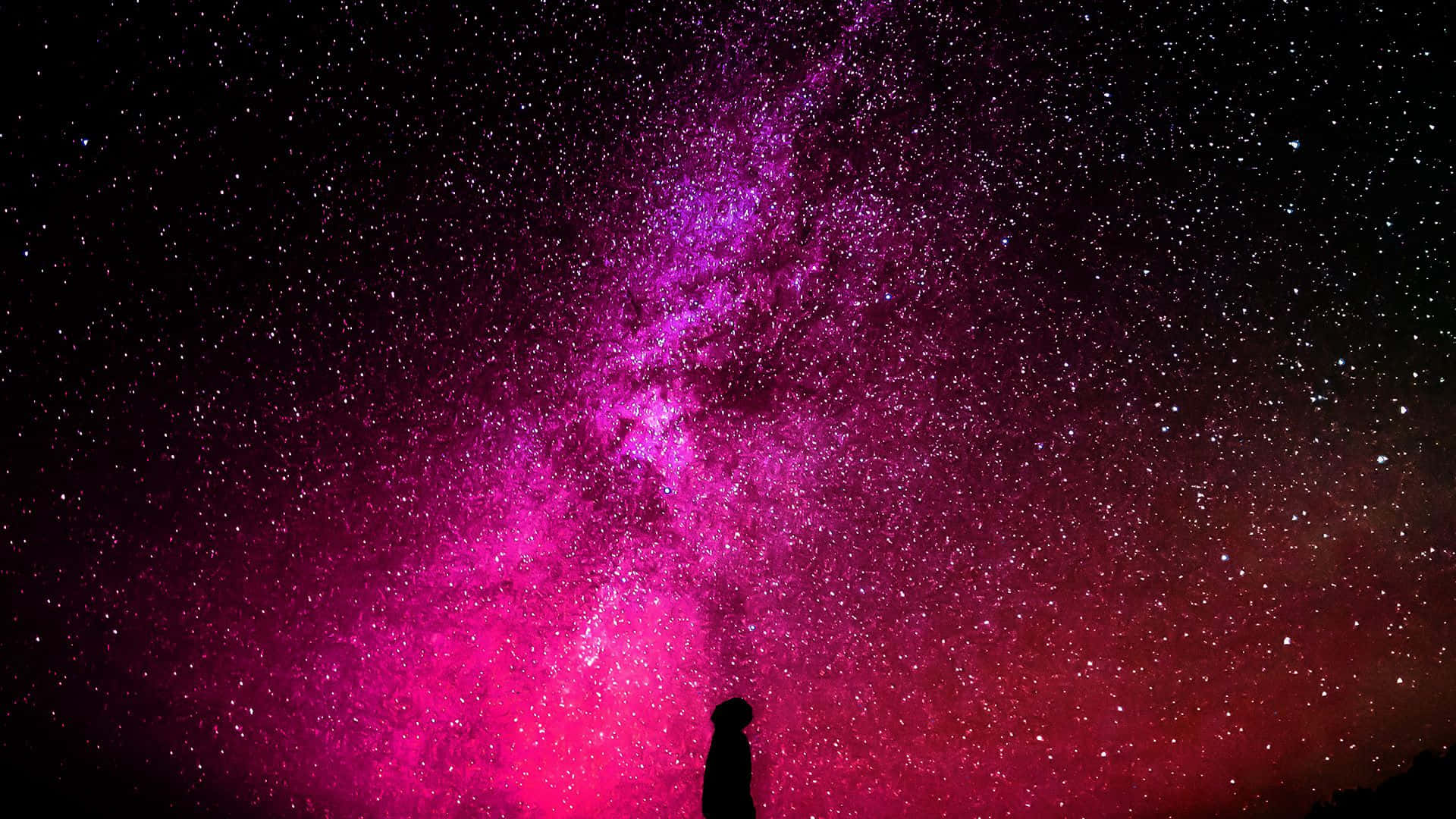 Pink Galaxy 桌布 壁紙 — 一個孤獨的剪影仰望橫跨星空夜空的鮮豔粉紅和紫色星系。