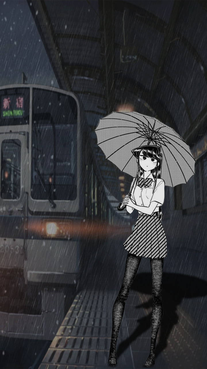 Komi San 桌布 壁紙 — 一個孤獨的動漫女孩拿著雨傘站在下雨的火車月台上，一列火車帶著發光的燈光駛近。