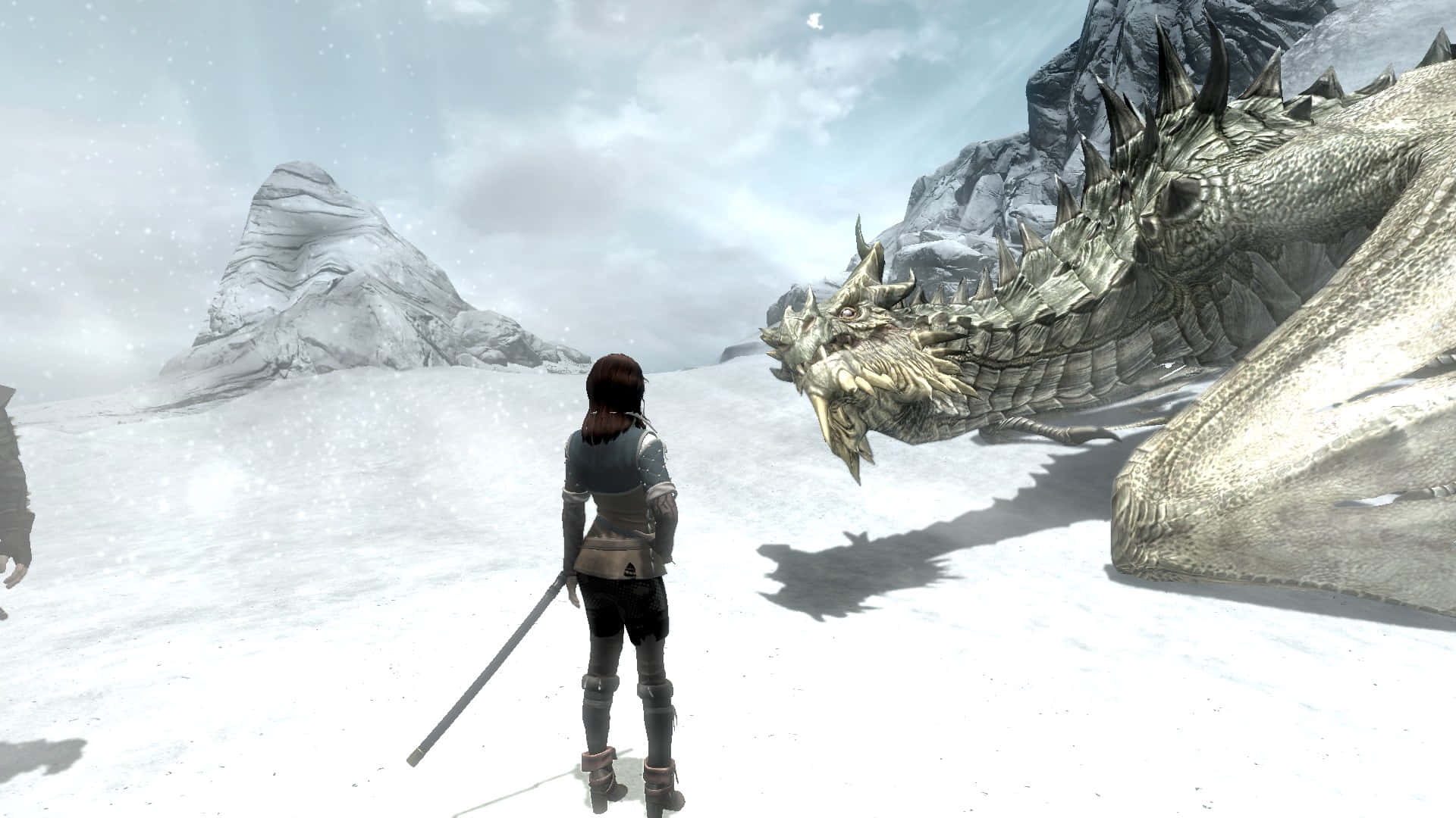 Skyrim Paarthurnax 桌布 壁紙 — 一個孤獨的戰士站在白雪覆蓋的山谷中，面對著一隻擁有尖刺鱗片和長長陰影的巨大冰龍。