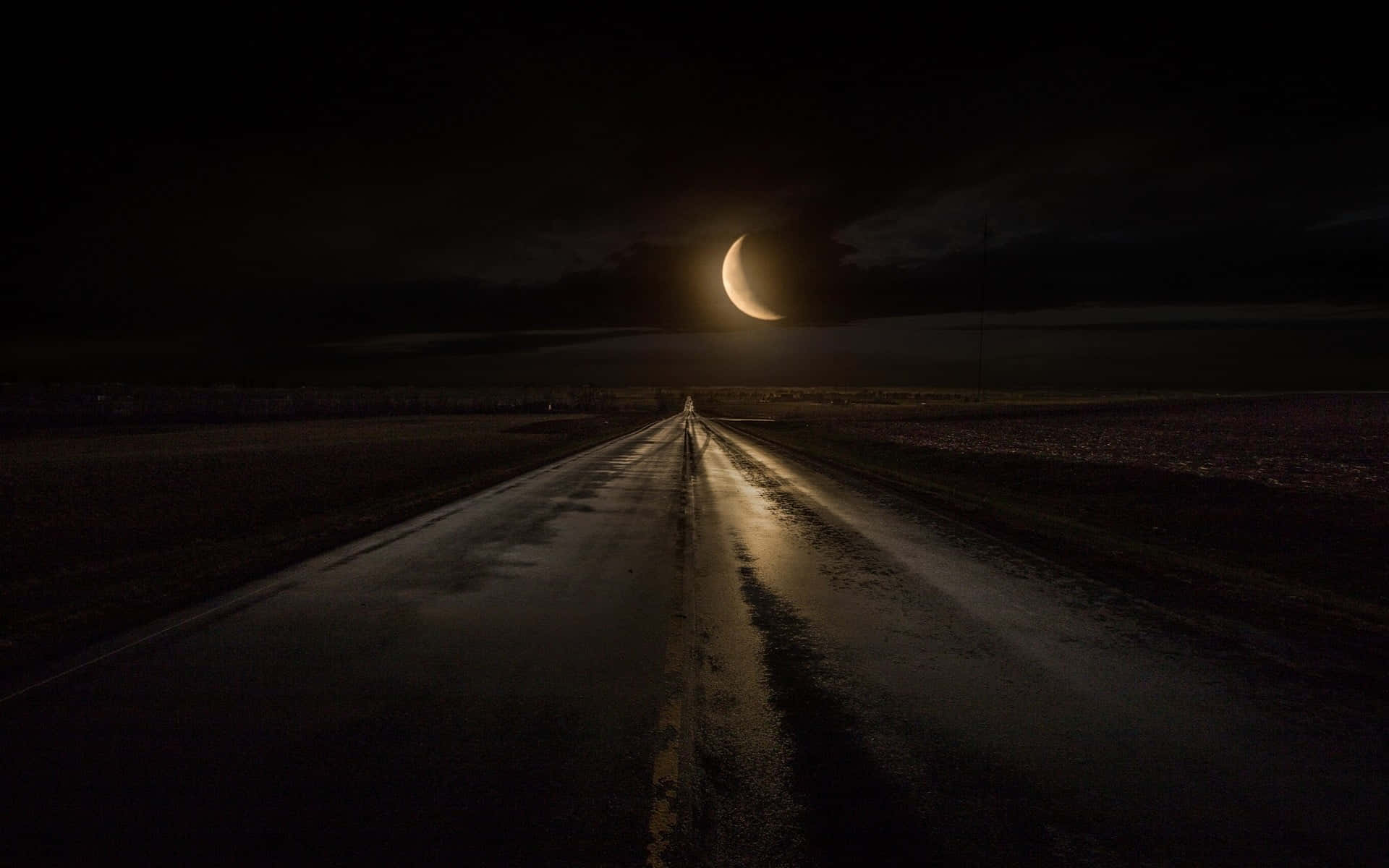 Dark Road 桌布 壁紙 — 一個孤獨的身影在夜晚沿著濕漉漉的道路行走，一輪發光的彎月投下長長的影子。