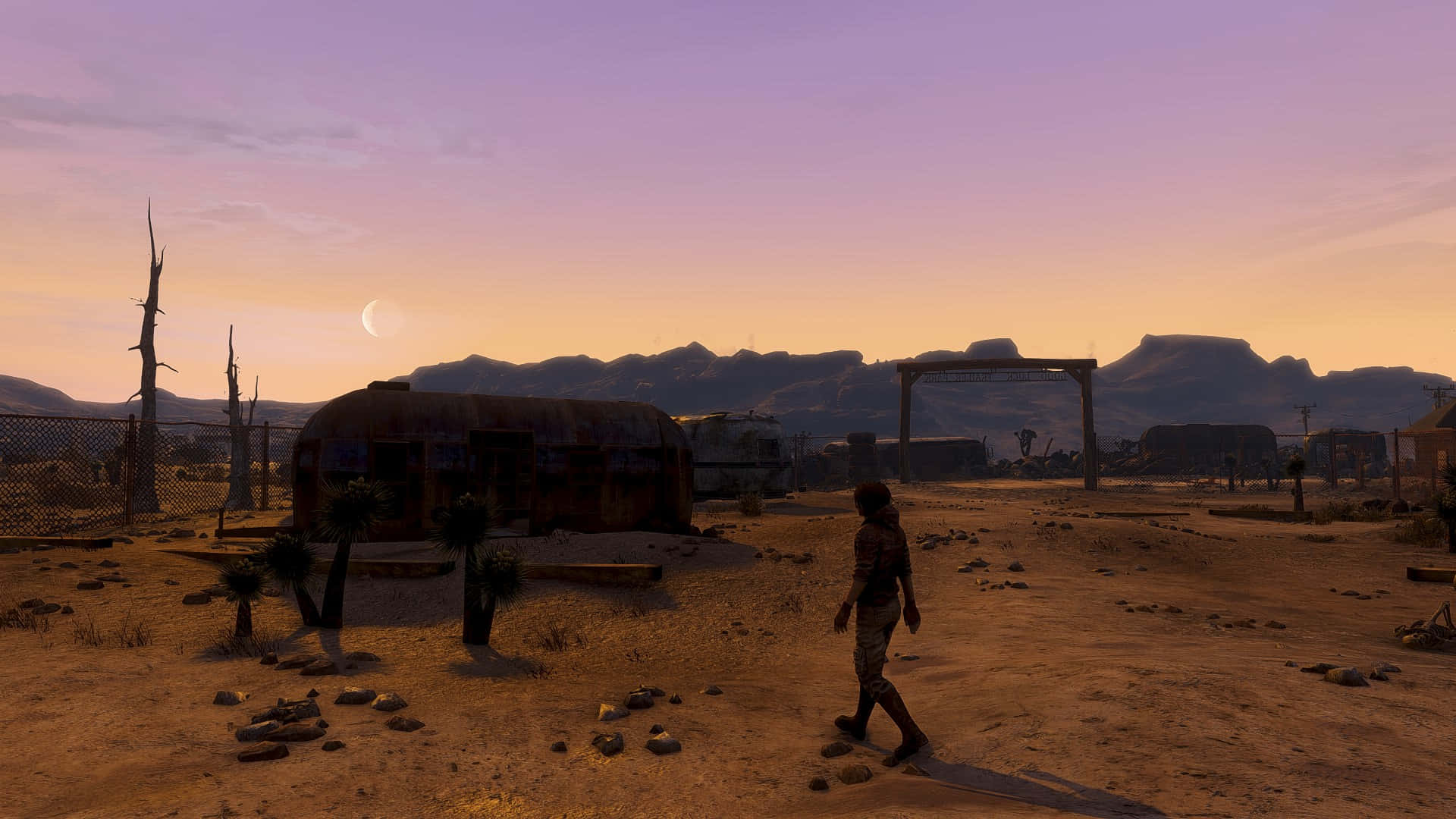 Fallout 4 Wasteland 桌布 壁紙 — 一個孤獨的身影在暮色中走過荒涼的沙漠荒地，經過生鏽的拖車和骨架般的樹木，新月高懸。