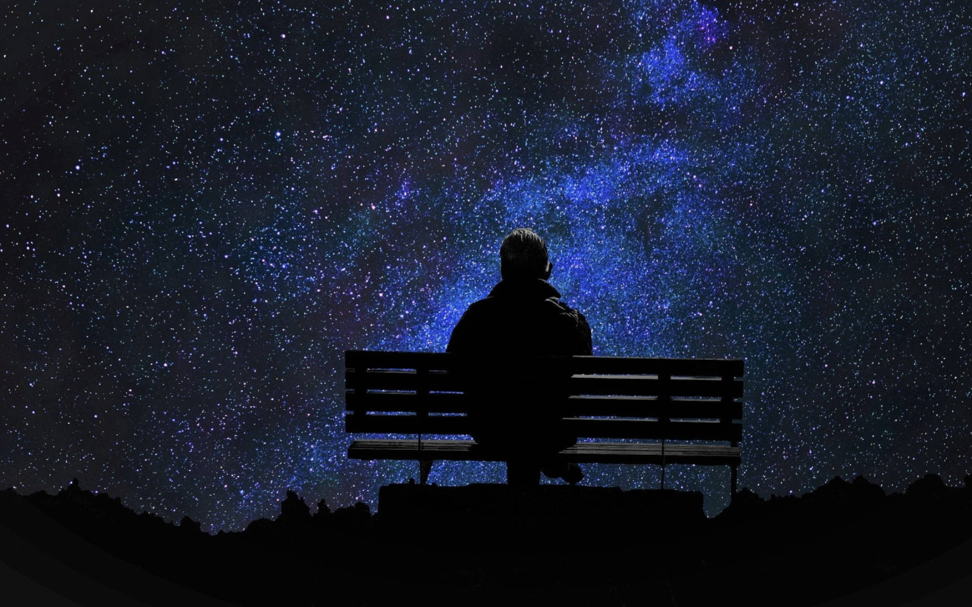 Alone 桌布 壁紙 — 一個孤獨的身影坐在長椅上，仰望充滿鮮豔藍色星雲的壯麗星空。