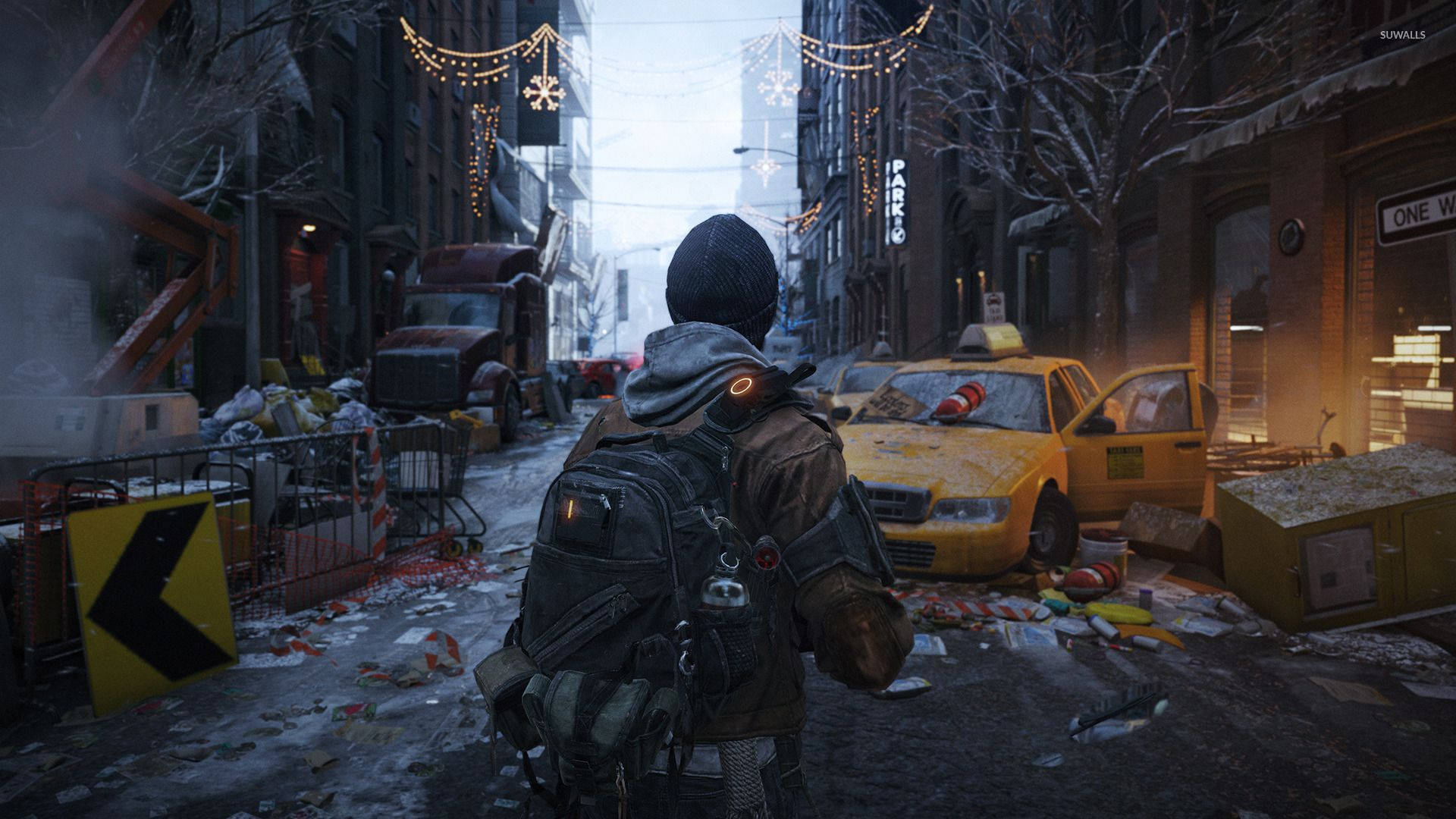 The Division 2 Ruined Street 壁紙 — 一個孤獨的身影穿著冬季裝備，走過一條積雪覆蓋、佈滿碎片的城市街道，有廢棄的黃色出租車和懸掛在頭頂的節日燈飾。
