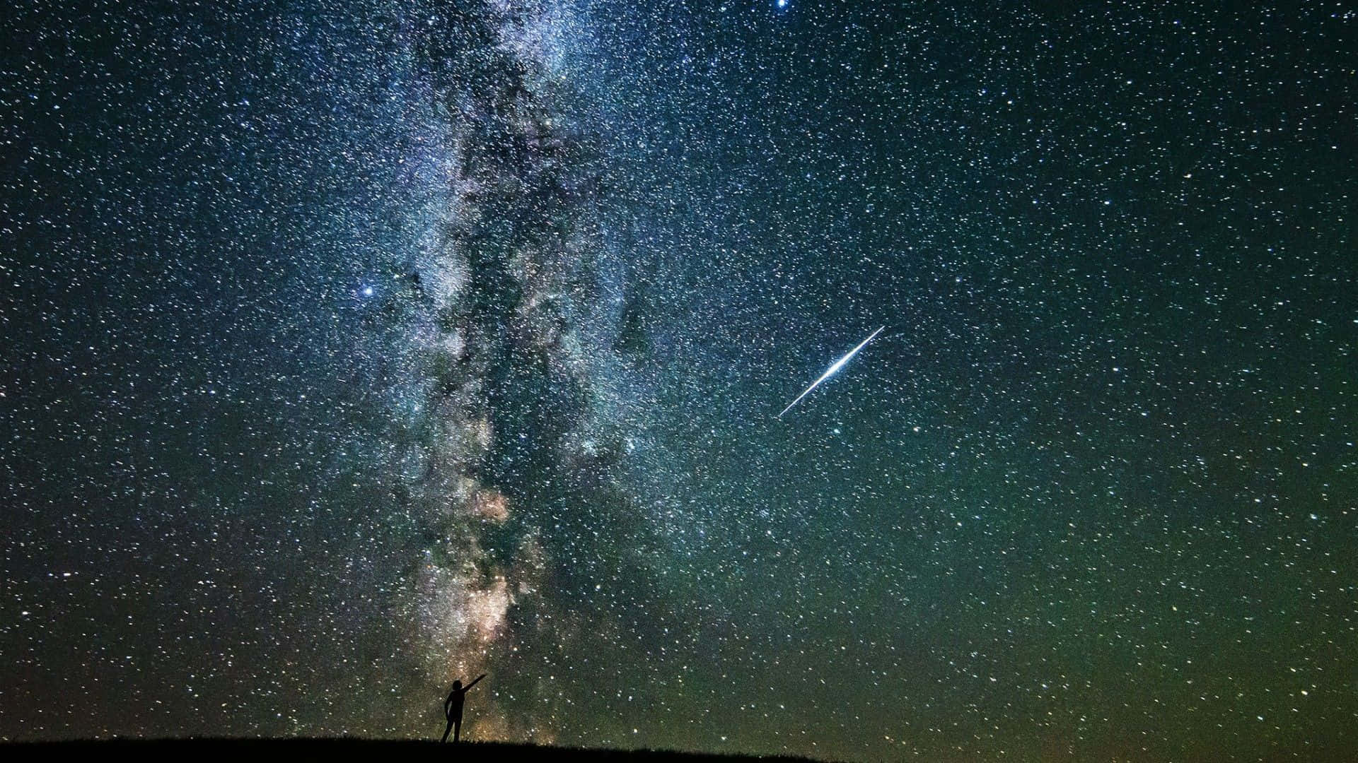 Beautiful Star 桌布 壁紙 — 一個孤獨的身影站在山丘上仰望銀河系，一顆明亮的流星劃過繁星點點的夜空。