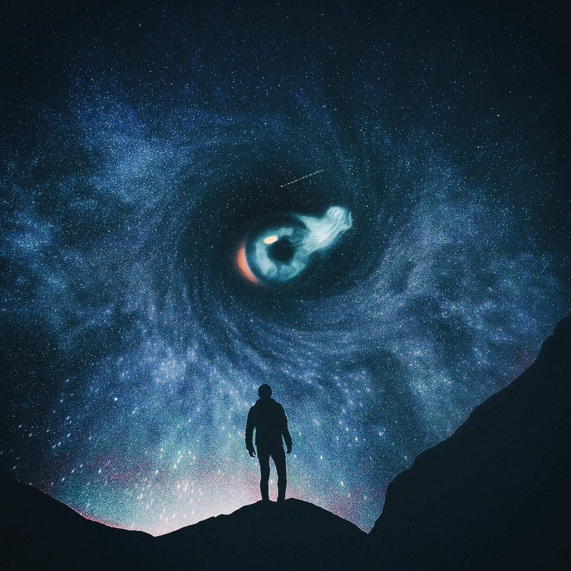 Silhouette 桌布 壁紙 — 一個孤獨的身影站在懸崖上，仰望一個由星星和星雲旋轉而成的宇宙之眼，呈現深藍和紫色調。