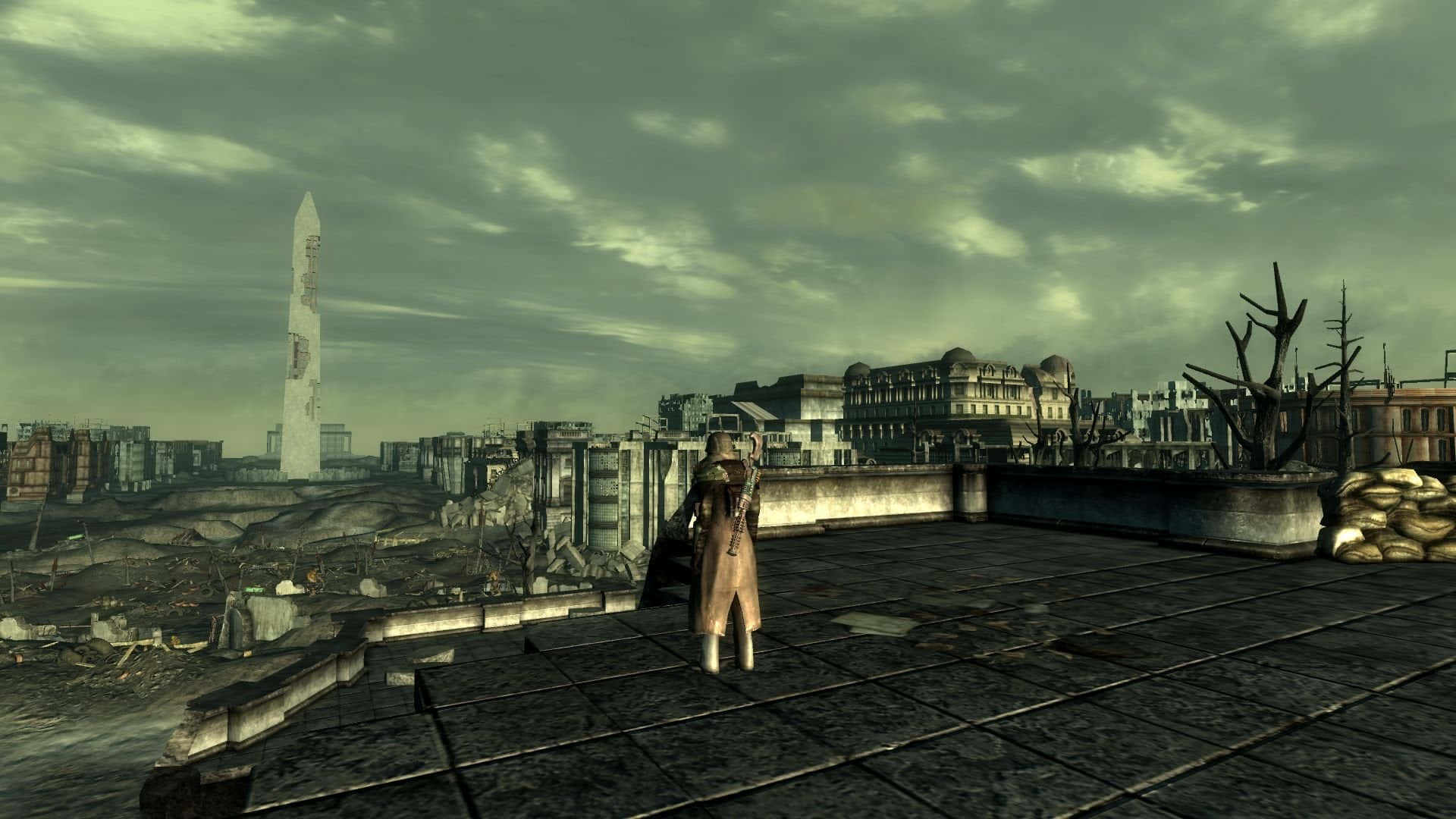 Fallout 4 The Capital Wasteland 桌布 壁紙 — 一個孤獨的身影站在破損的屋頂上，俯瞰著陰沉天空下荒涼的末日後城市景觀。