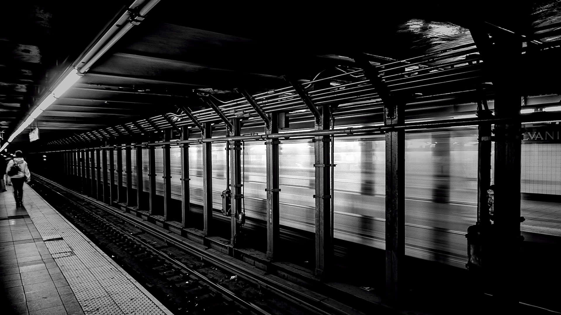 Motion Blur 桌布 壁紙 — 一個孤獨的身影走過一個鮮明的黑白地鐵站，一列高速列車在運動中模糊掠過。