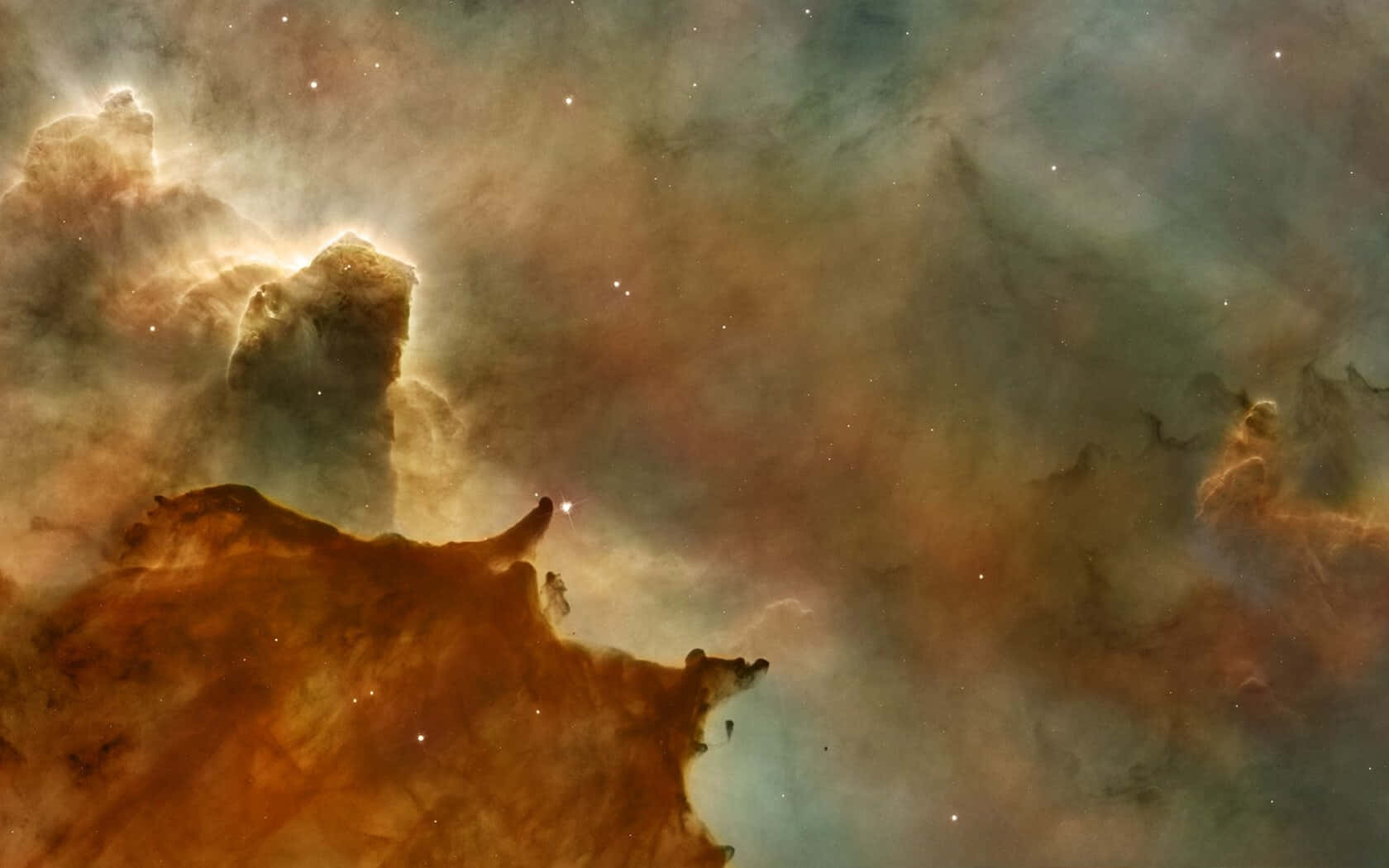 Carina Nebula 桌布 壁紙 — 一個宇宙星雲，帶有發光的橙色和藍綠色雲層，形狀像高聳的柱子和剪影尖塔，背景是星場。