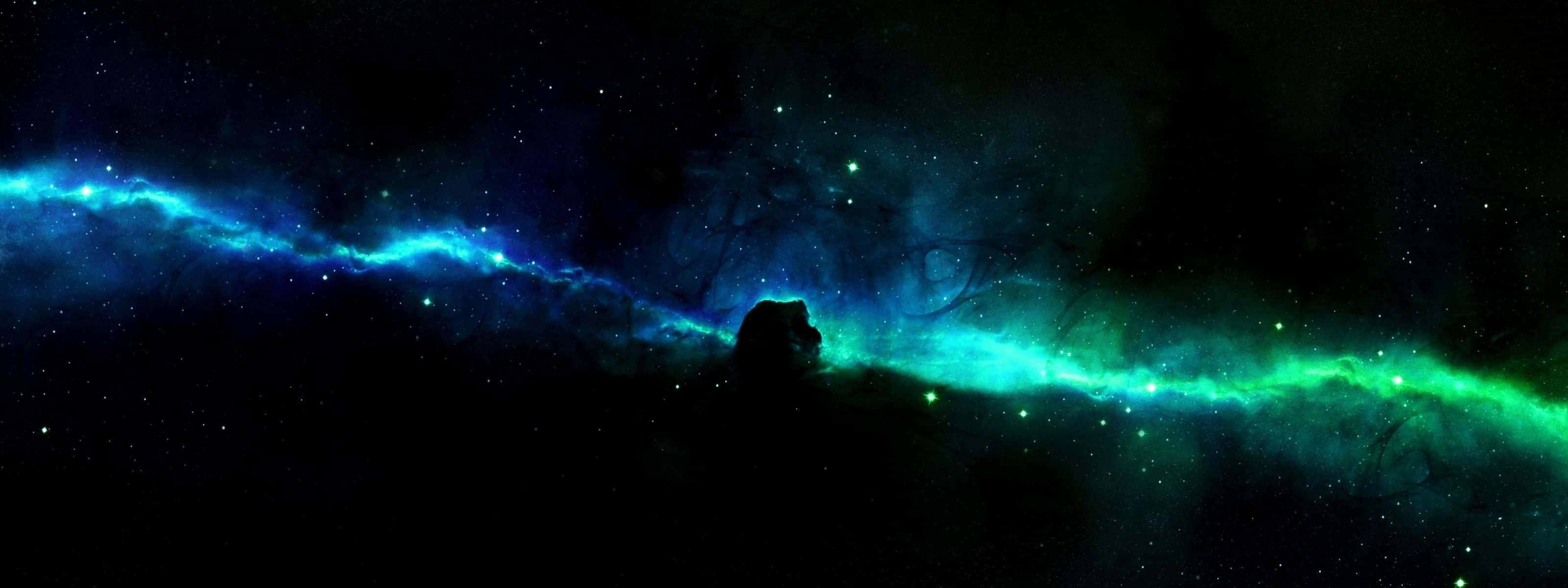 雙螢幕 桌布 壁紙 — 一個宇宙星雲，帶有發光的藍色和綠色卷鬚，橫跨星空，前景有一個黑暗的剪影。