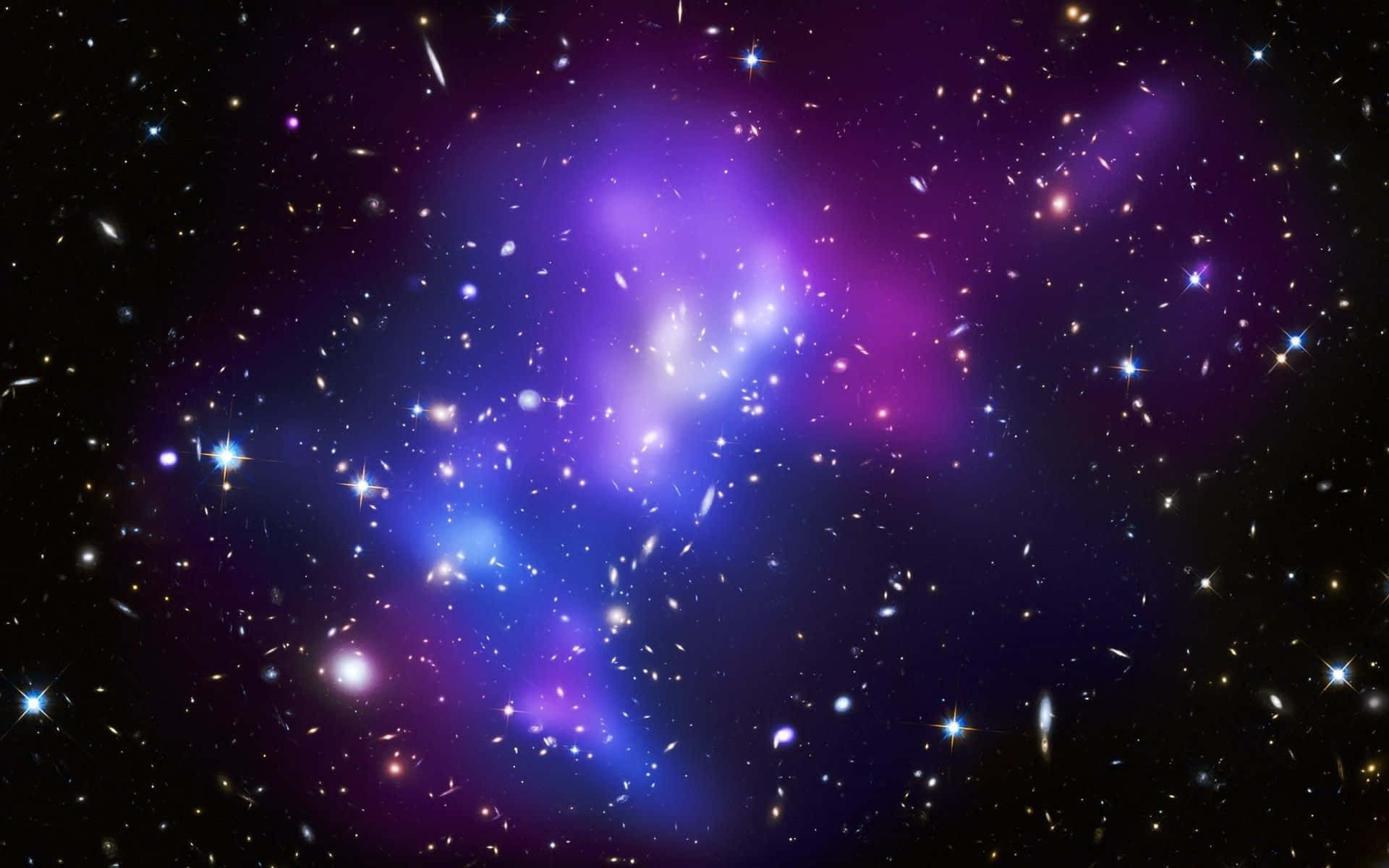 Purple Galaxy 桌布 壁紙 — 一個宇宙星雲，散發著充滿活力的紫色和藍色色調，被無數閃爍的星星包圍，背景是深邃的黑色虛空。