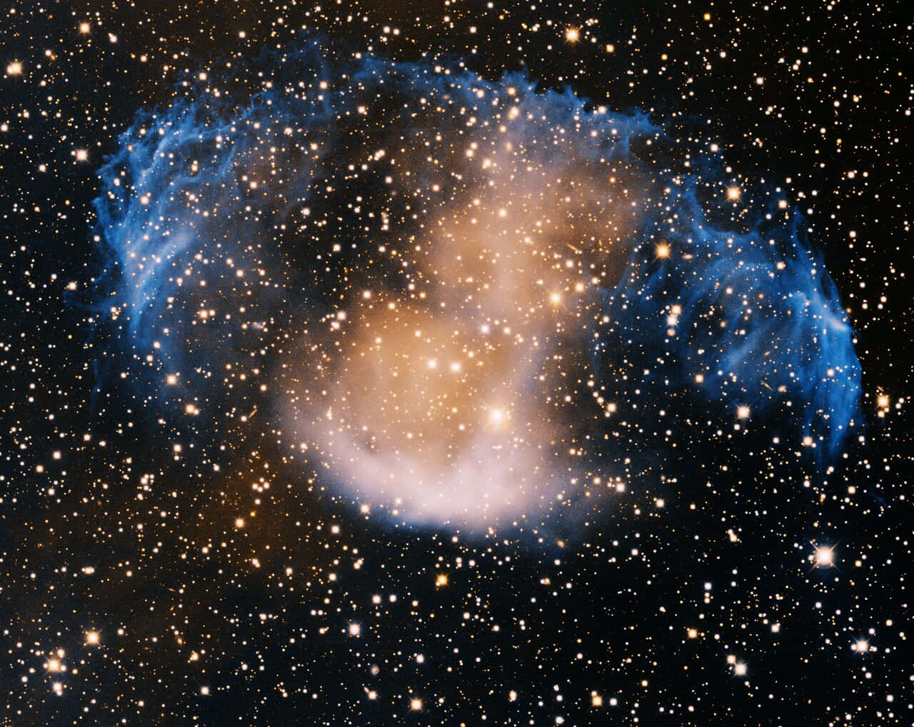 Planetary Nebula 桌布 壁紙 — 一個宇宙星雲，有旋轉的藍色和金色雲彩，被無數星星照亮，背景是深邃的黑色虛空。