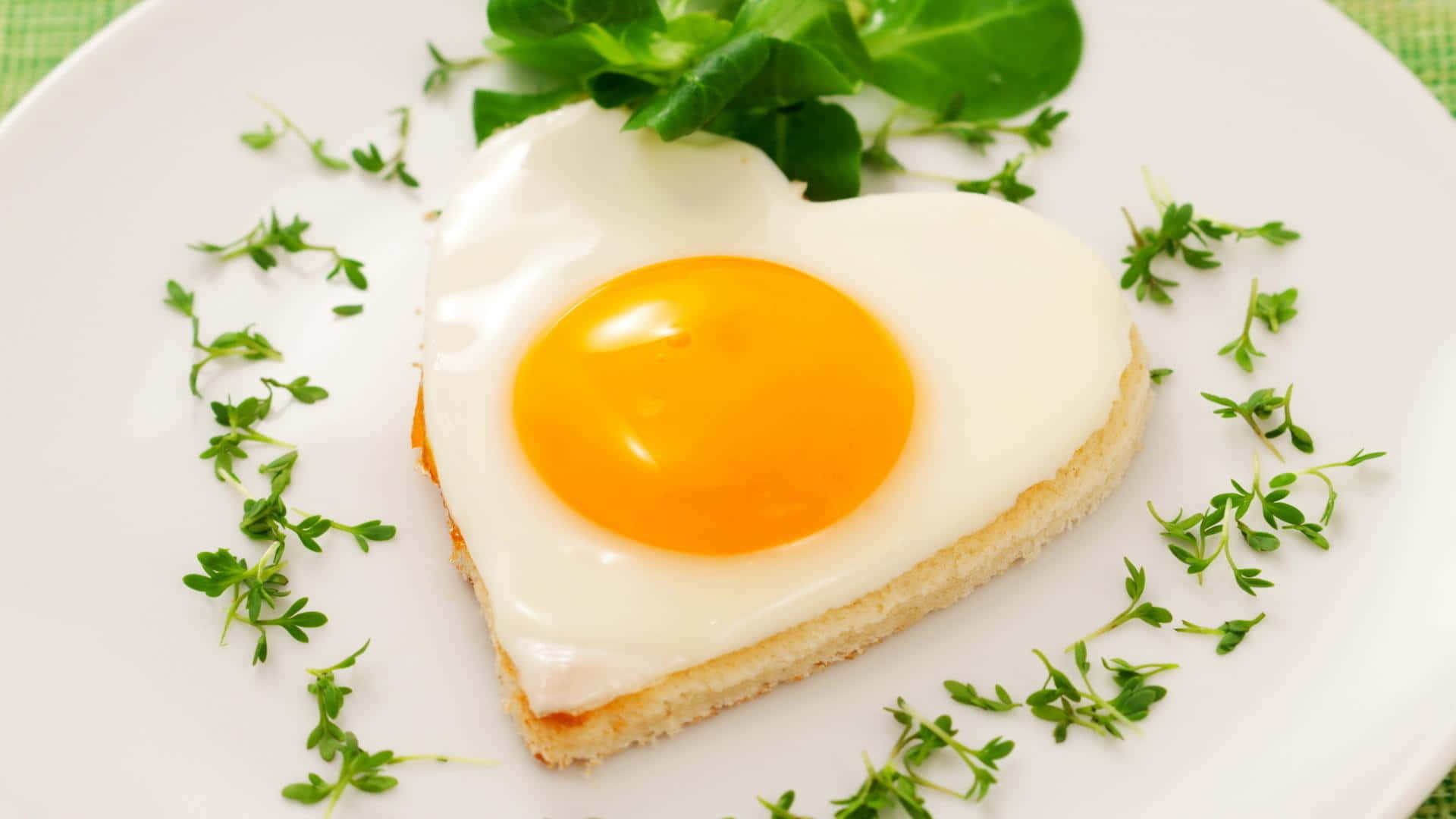 Egg 桌布 壁紙 — 一個完美煎成心形的雞蛋，帶有鮮豔的蛋黃，放在一片吐司上，飾以新鮮百里香，置於白色碟中。