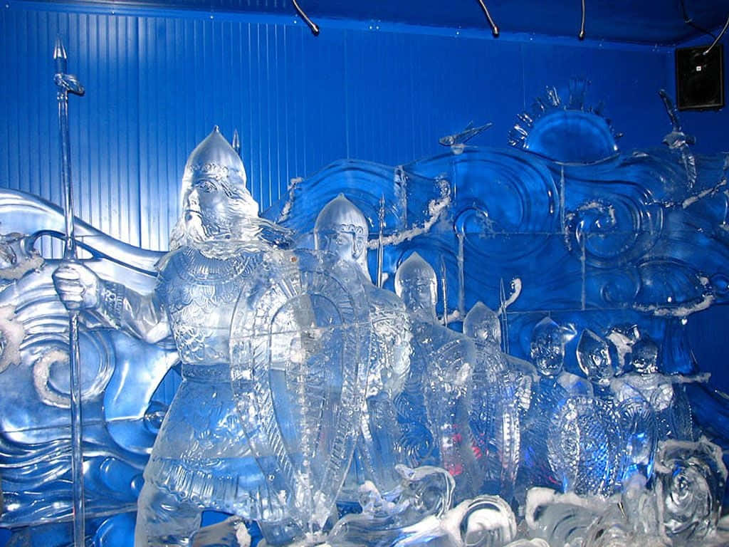 Ice Sculpture 桌布 壁紙 — 一個宏偉的冰雕，描繪身穿盔甲的騎士手持寶劍，在明亮的燈光下矗立在旋轉的藍色冰背景前。