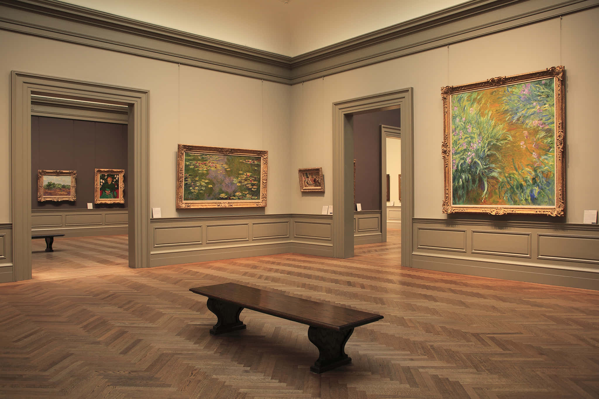 Museum 桌布 壁紙 — 一個宏偉的博物館畫廊，舖有人字紋木地板和華麗畫框，在柔和環境燈光下展示充滿活力的印象派畫作。
