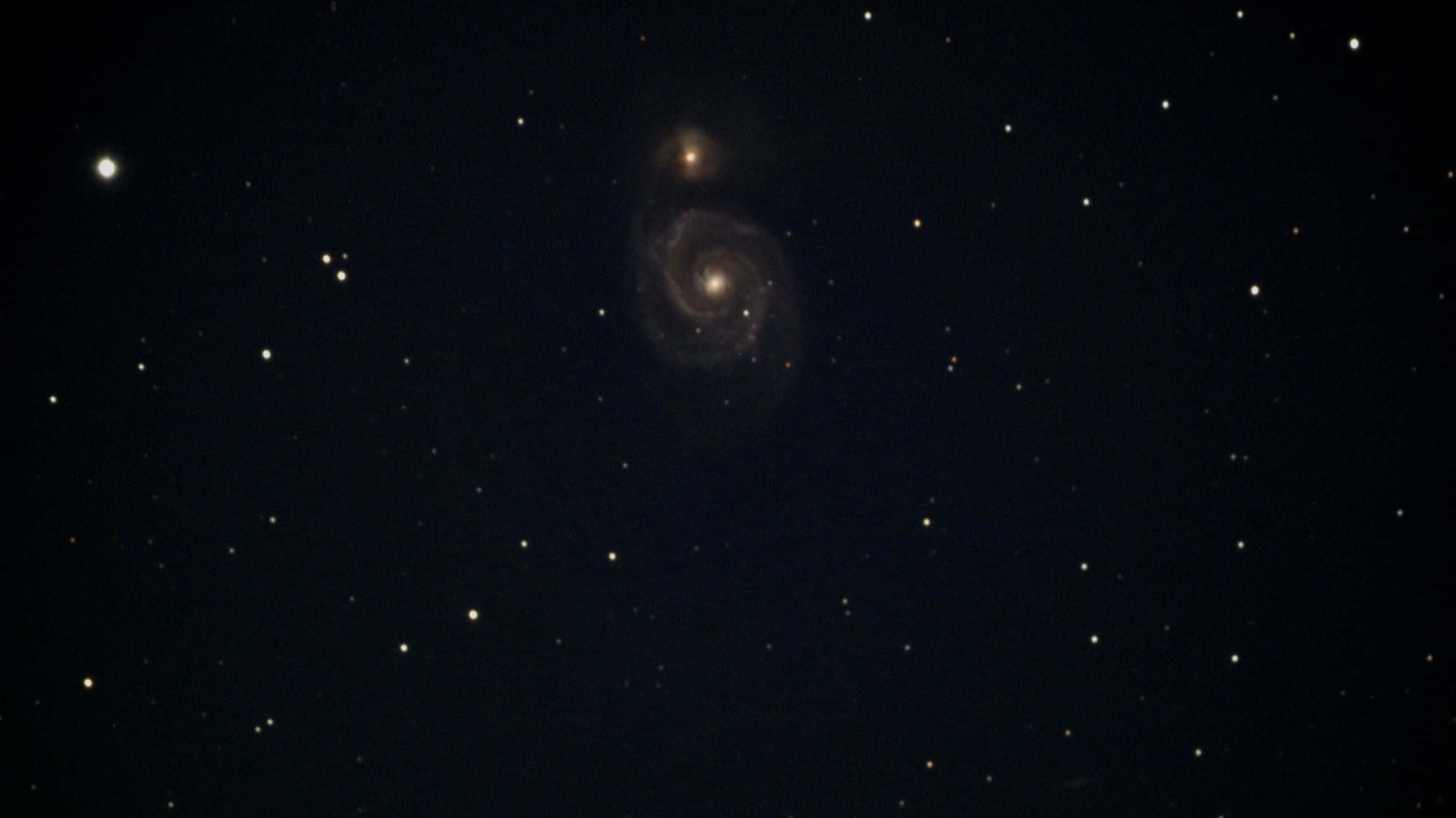Whirlpool Galaxy 桌布 壁紙 — 一個宏偉的螺旋星系在繁星點點的宇宙夜空中閃耀著金色光芒。