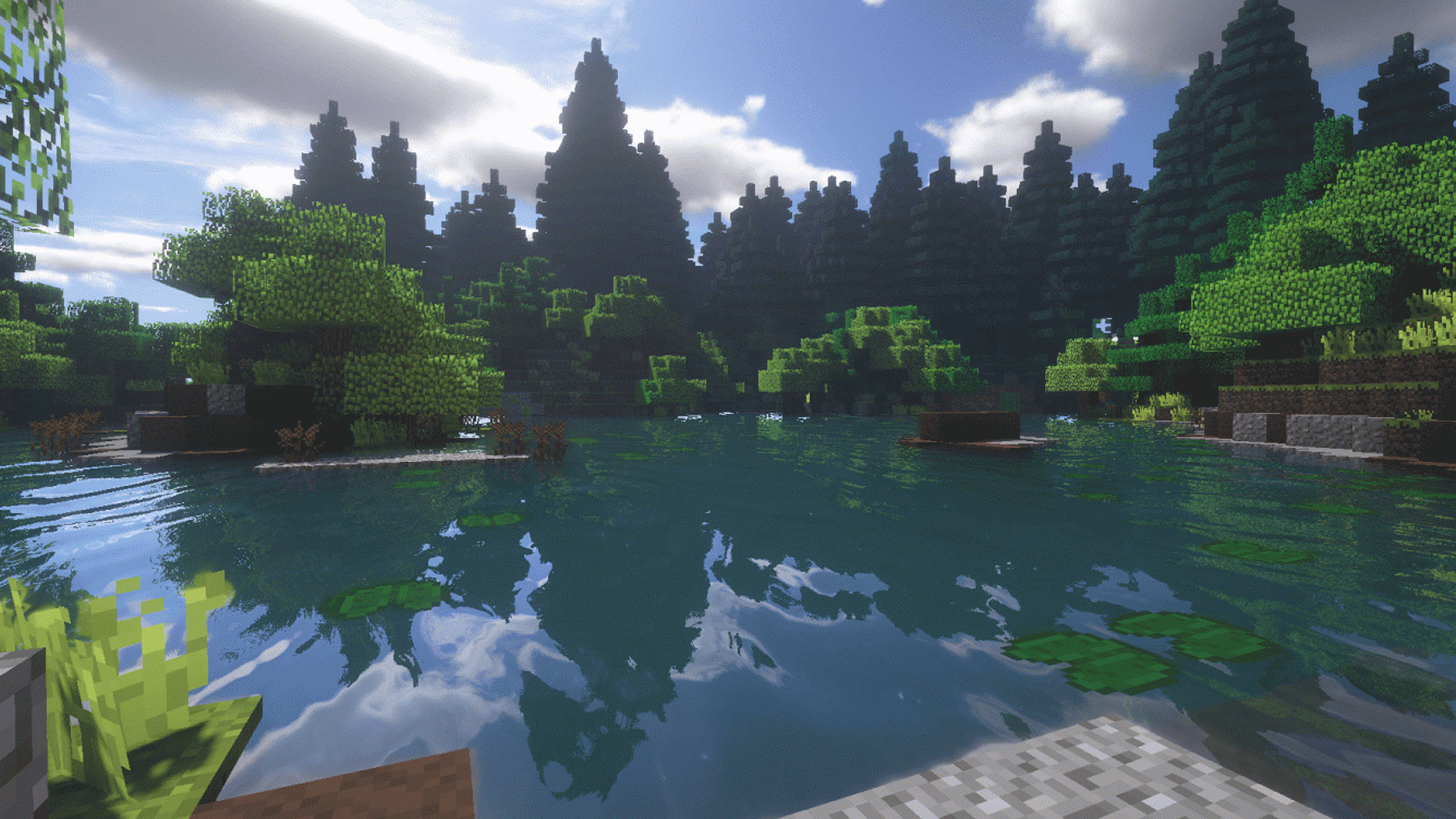 遊戲 桌布 壁紙 — 一個寧靜的Minecraft湖泊，周圍是像素化的綠色樹木，天空部分多雲的藍天。