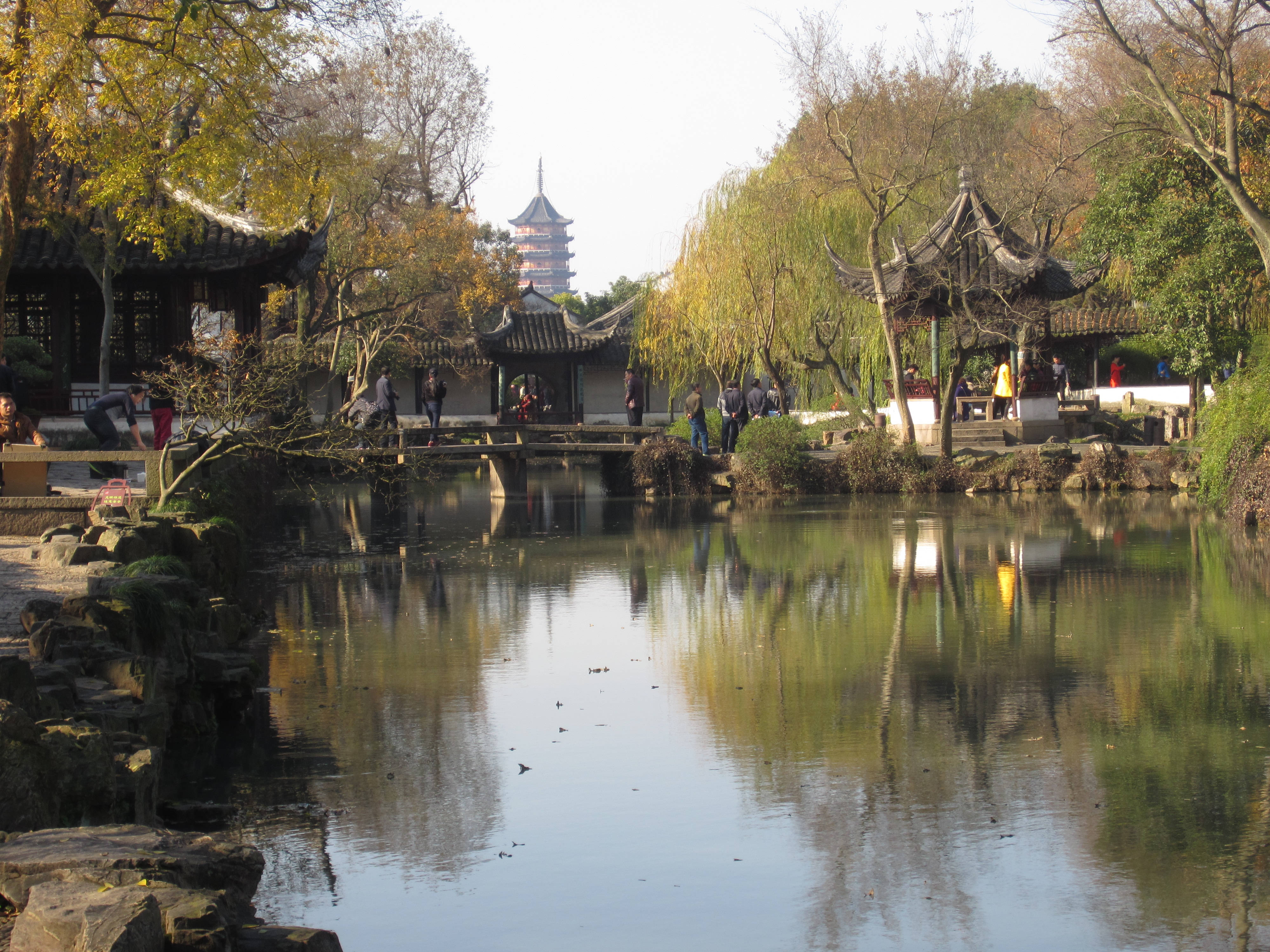 Garden 桌布 壁紙 — 一個寧靜的中式花園池塘，在秋葉金黃的樹下倒映著傳統亭台樓閣和一座寶塔。